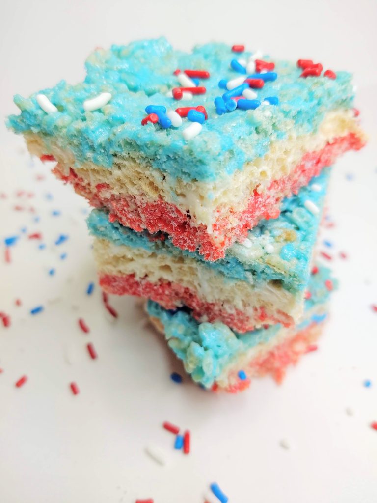 3 red, white, and blue rice krispie treats stacked on top of each other with sprinkles around them