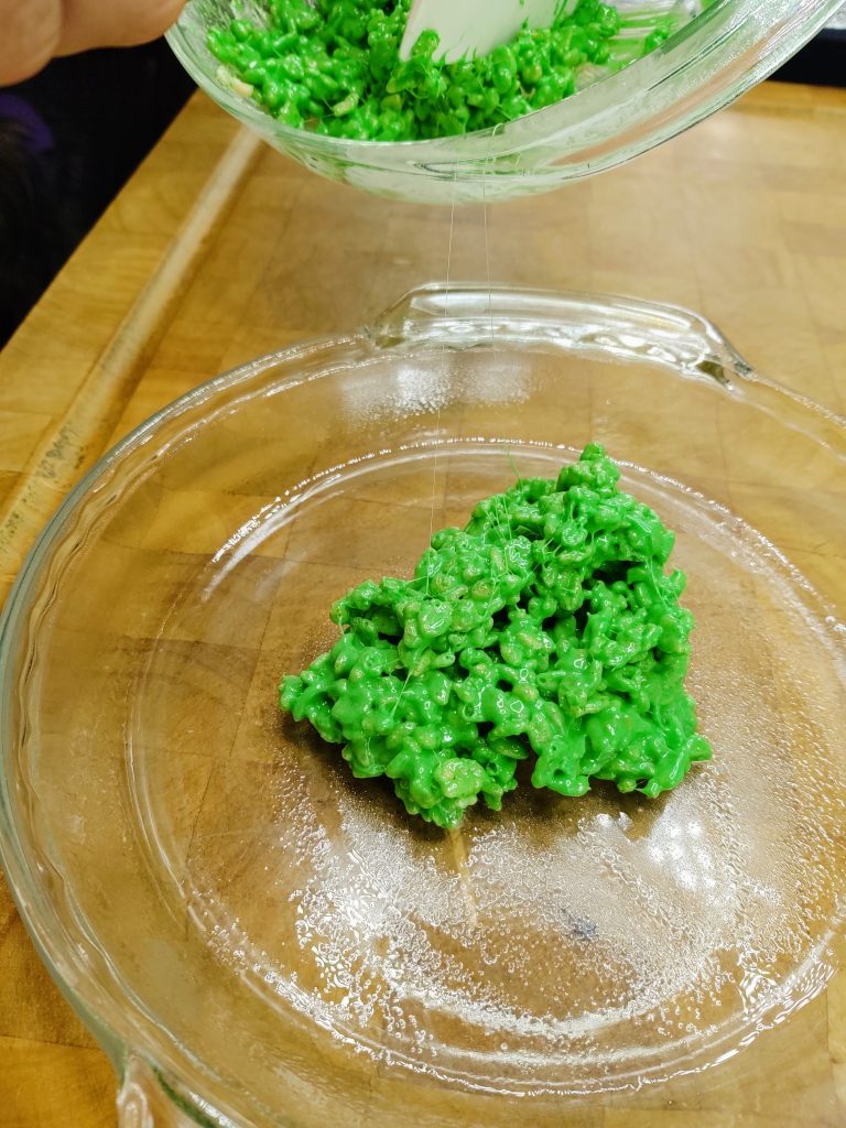 blob of green rice krispie treat mix in center of pie pan