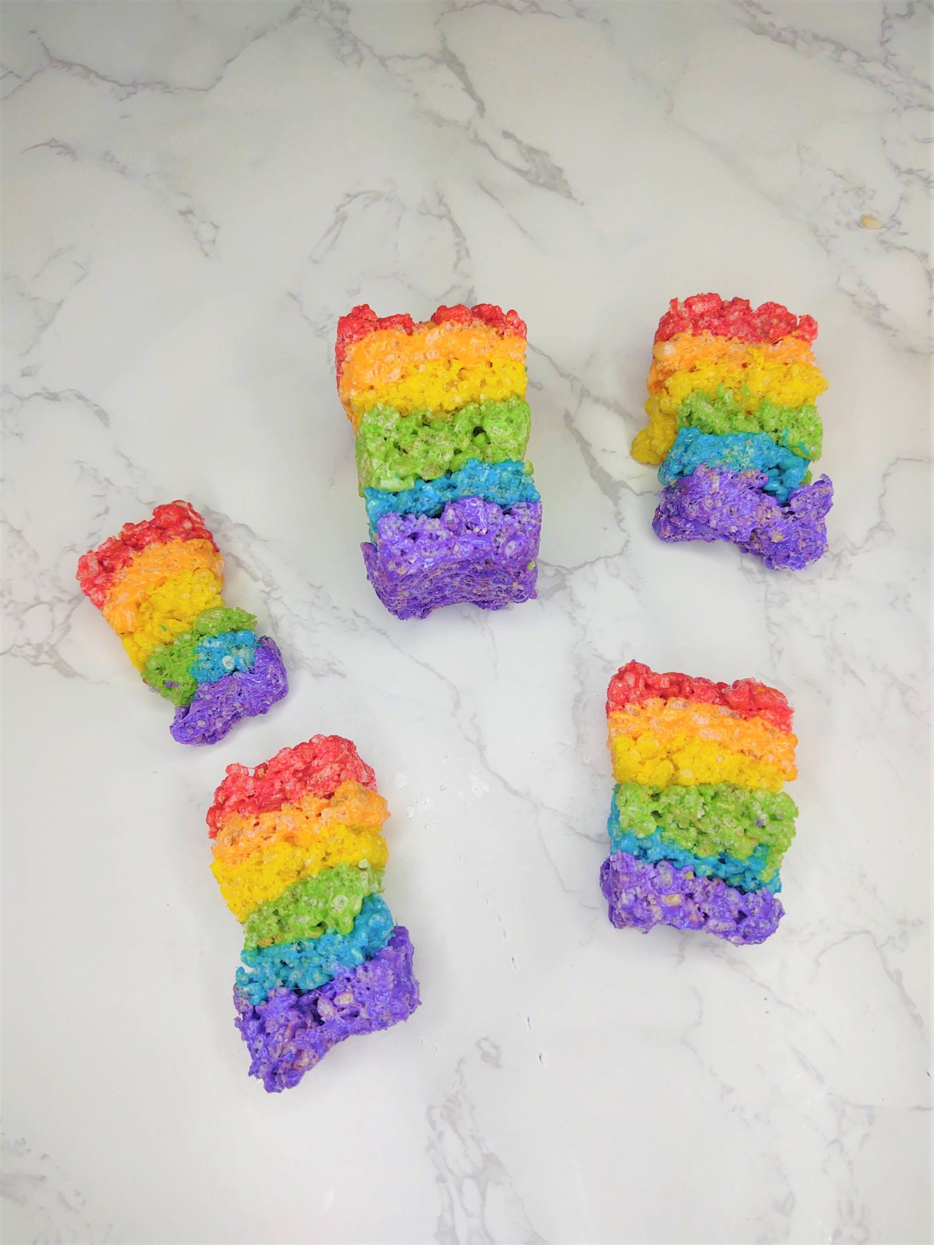 5 Rainbow Rice Krispie Treats on a marble table