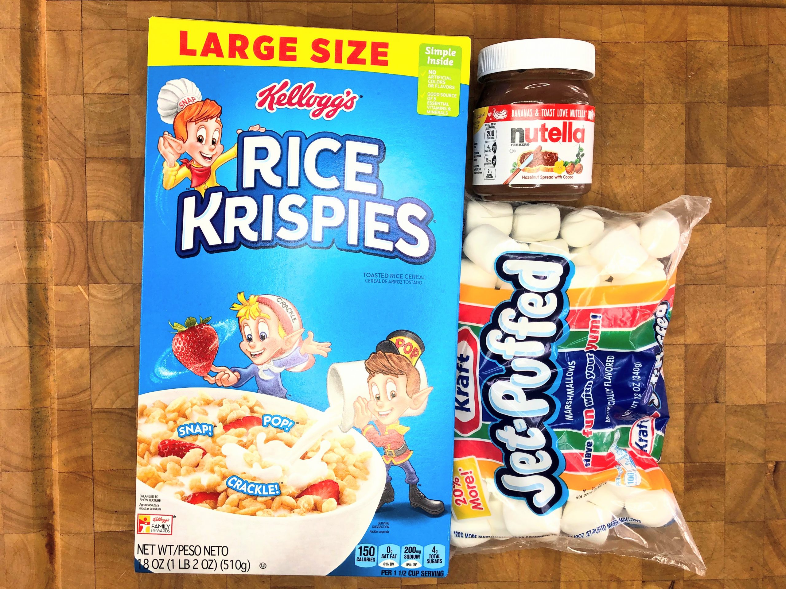 box of rice krispies, jar of nutella and bag of marshmallows on a wooden table