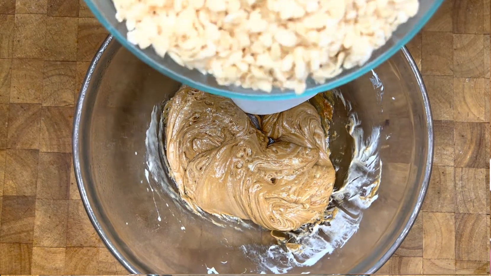 pouring rice krispie cereal into melted marshmallows and bischoff spread