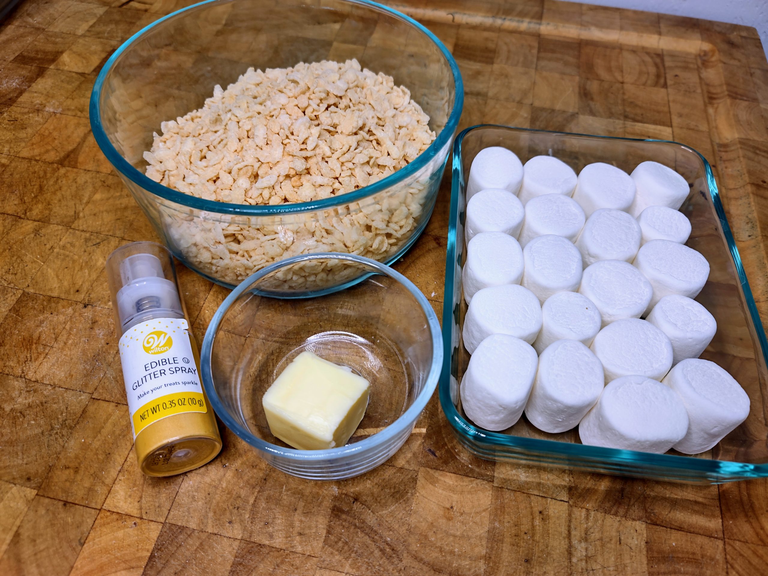 bowl of rice krispie cereal, marshmallows, butter and edible gold glitter spray