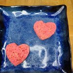 two pink heart rice krispie treats on a blue plate