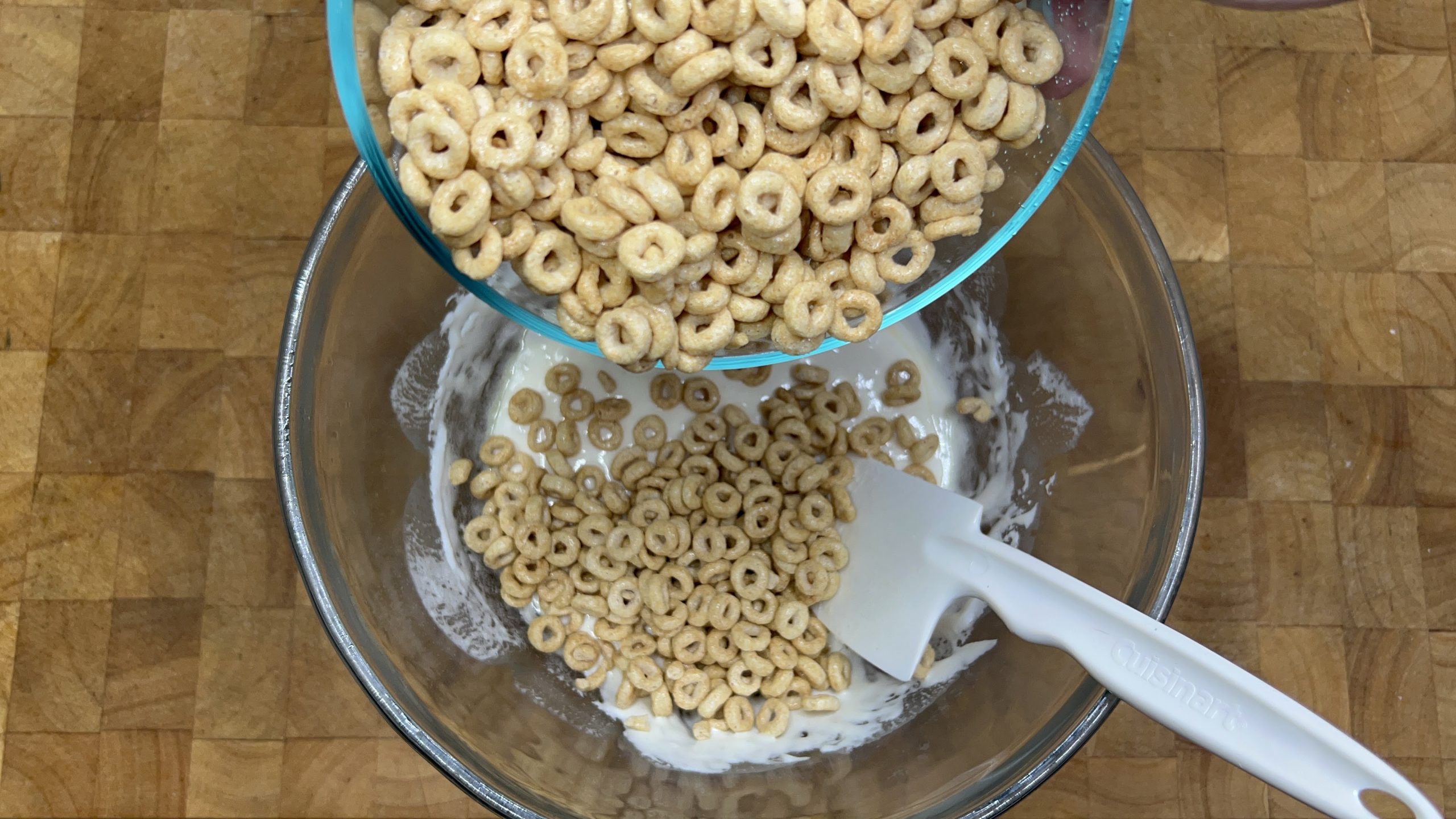 adding cheerios to melted marshmallows