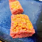 line of pink and gold rice krispie treats on a blue plate