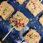 six rice krispie treats on sticks on a blue plate