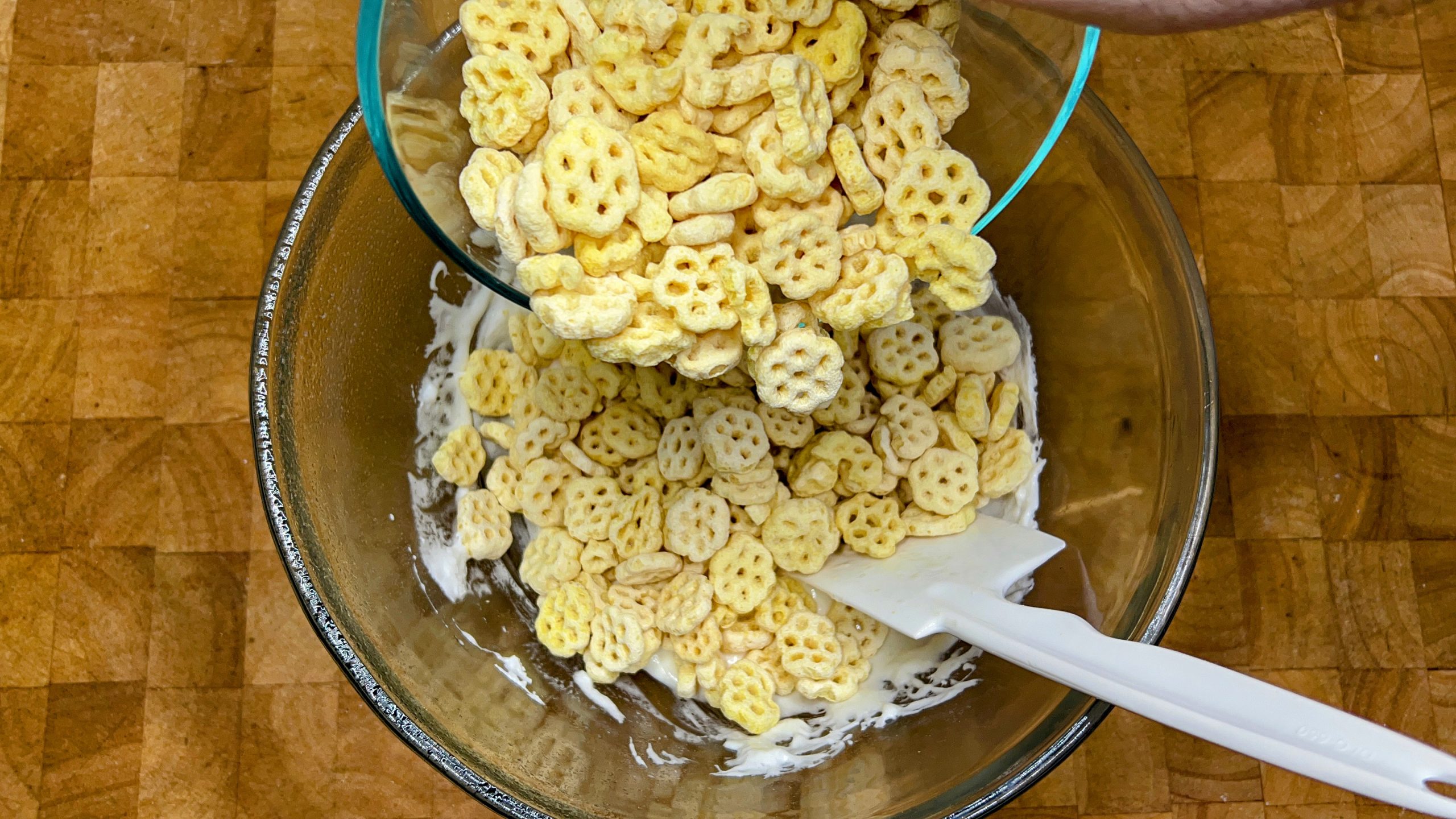 adding honeycomb cereal to melted marshmallows