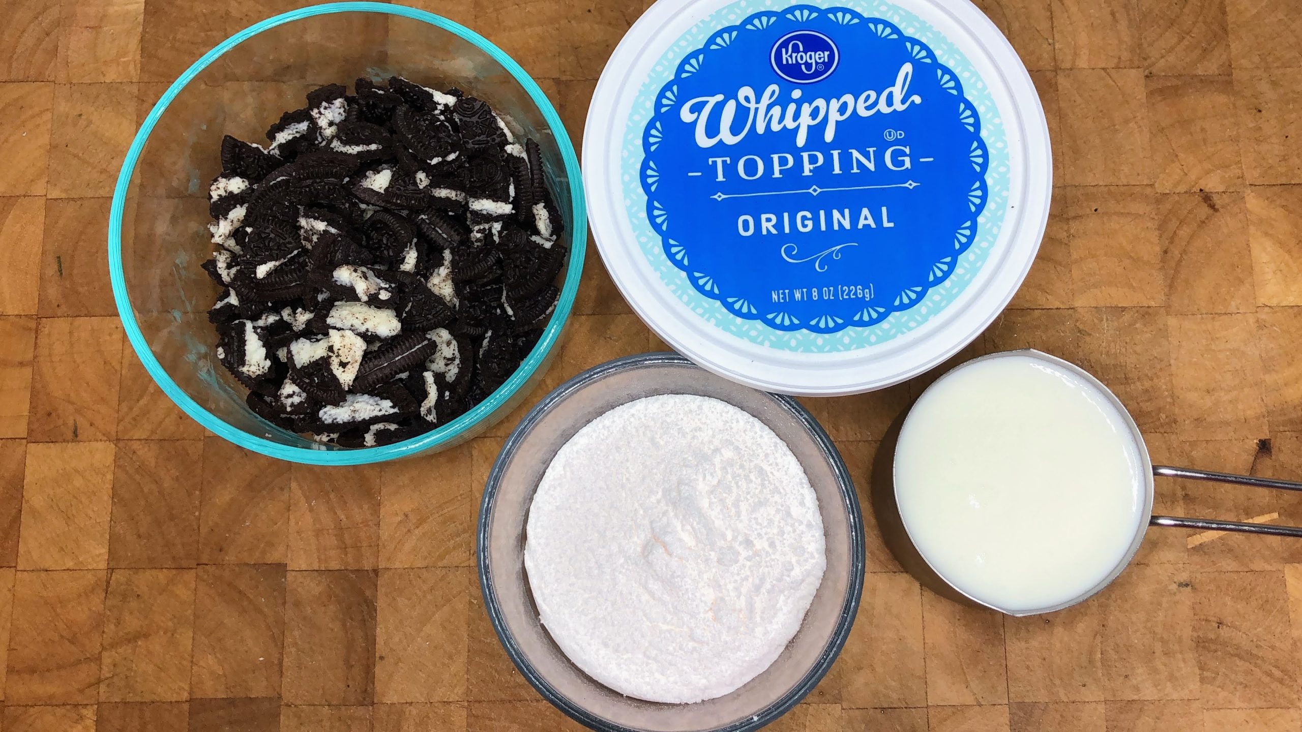 Bowls of crumbled oreos, vanilla pudding, milk and whipped topping.