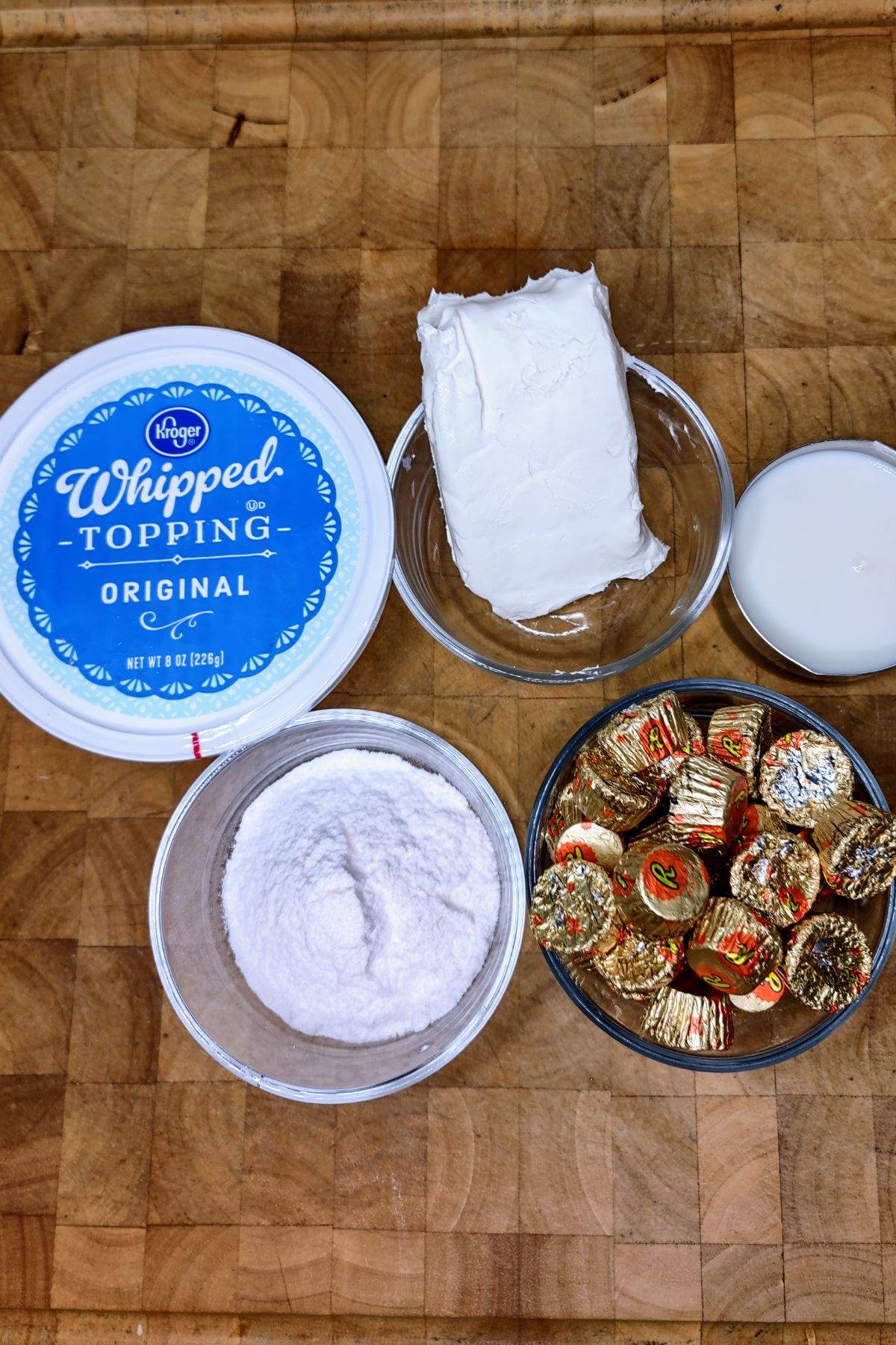 Bowls of powdered sugar, peanut butter cups, milk, cream cheese and whipped topping.