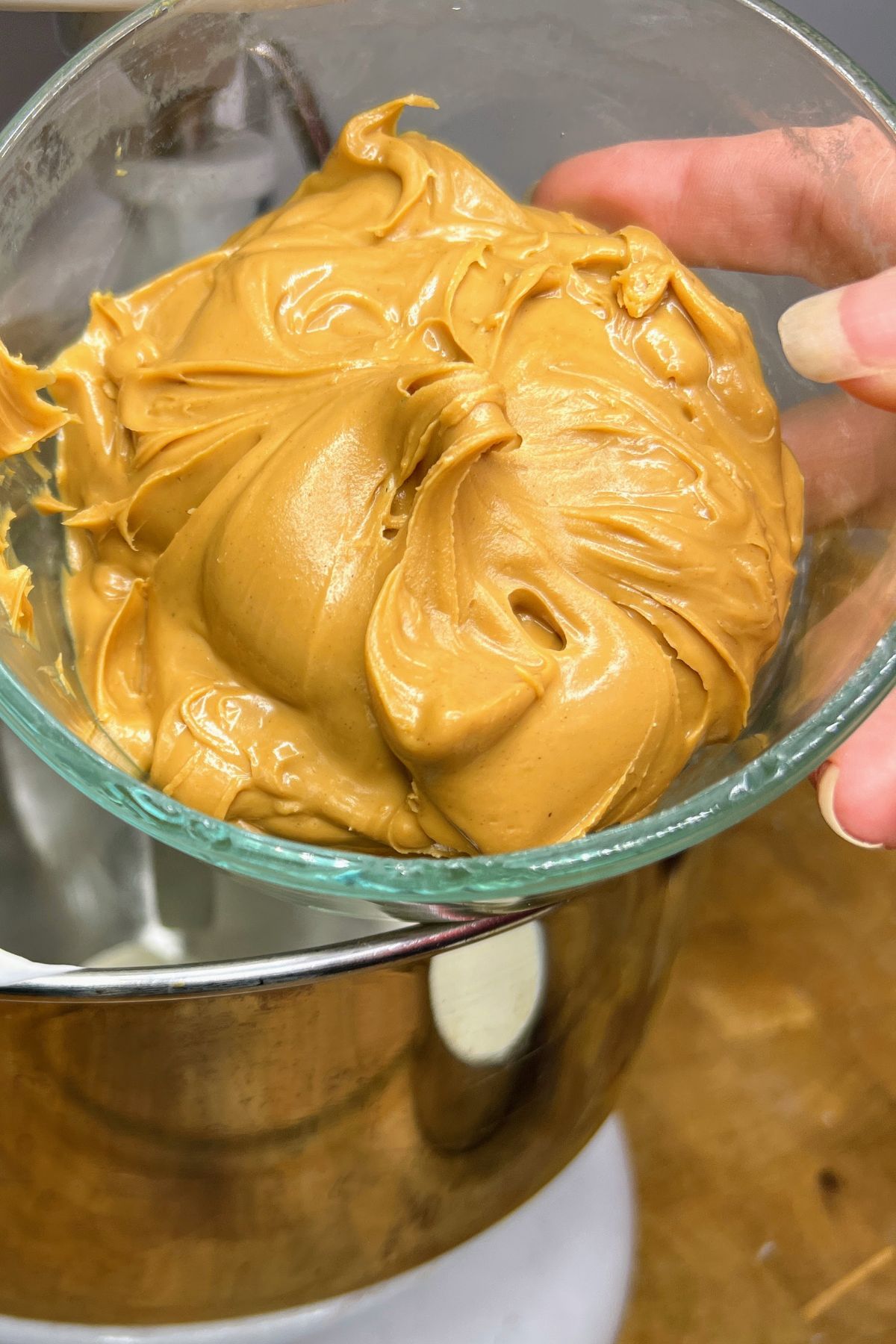A bowl full of peanut butter being held up.