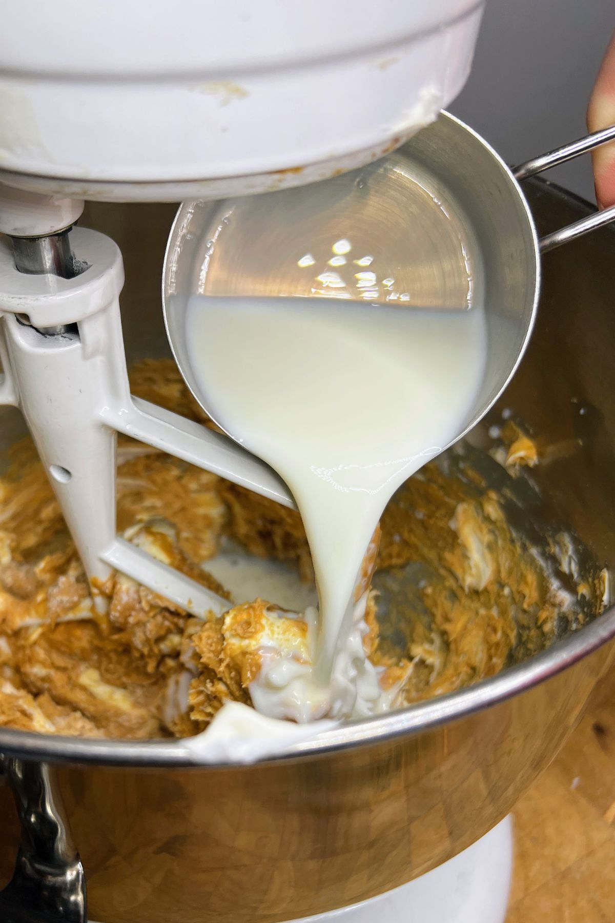 Pouring milk into peanut butter in a mixing bowl.