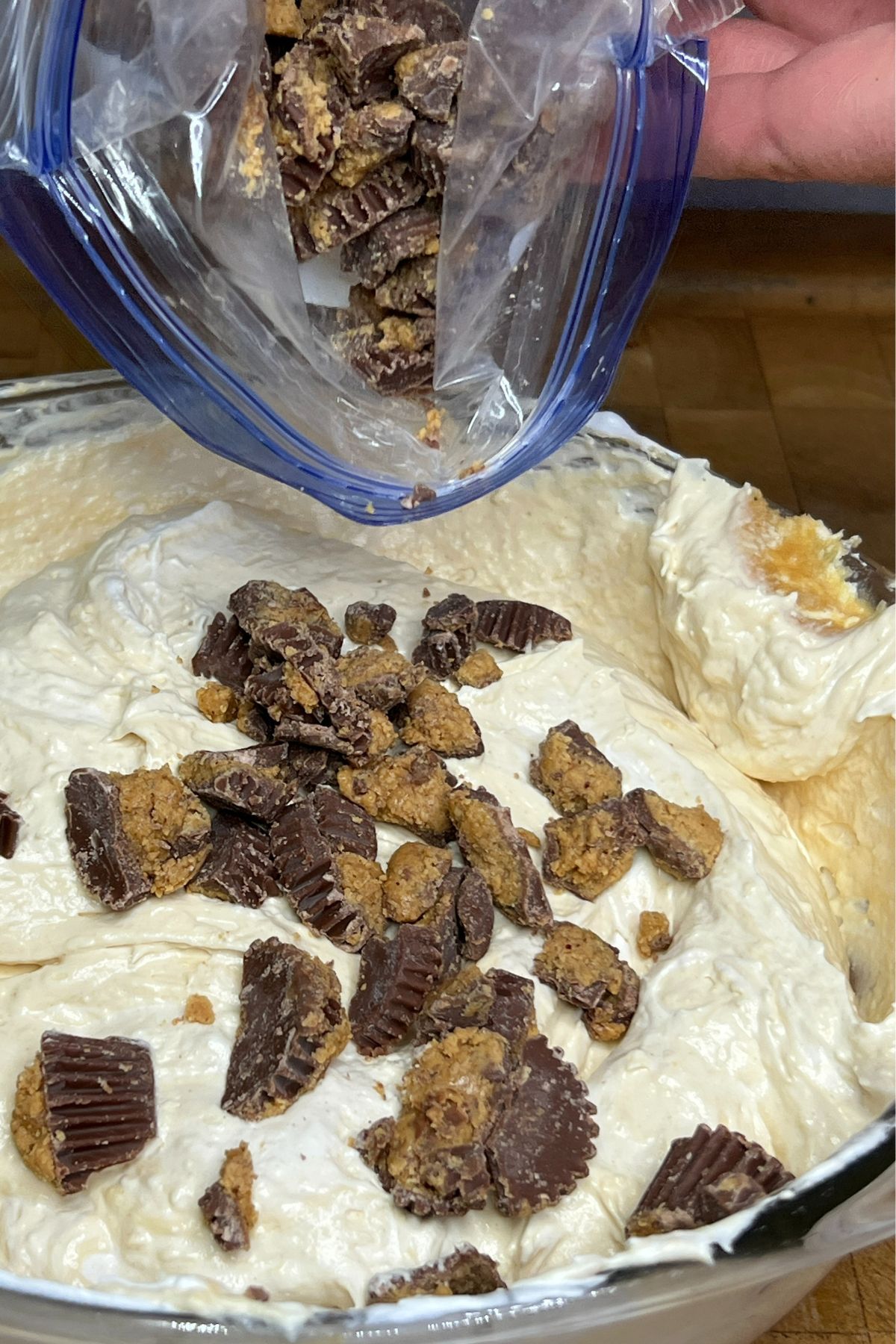 Pouring crumbled peanut butter cups into fluff.