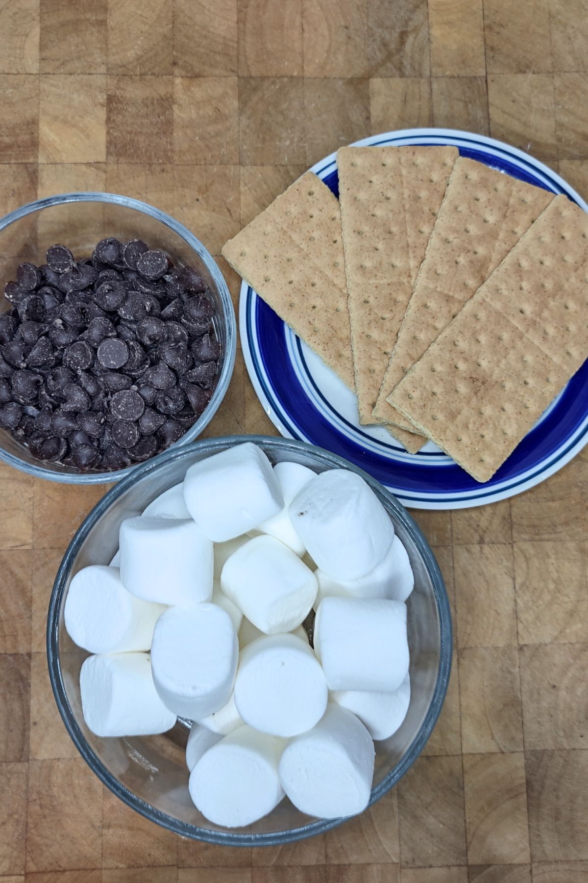 Bowls of chocolate chips, marshmallows and a plate of graham crackers.