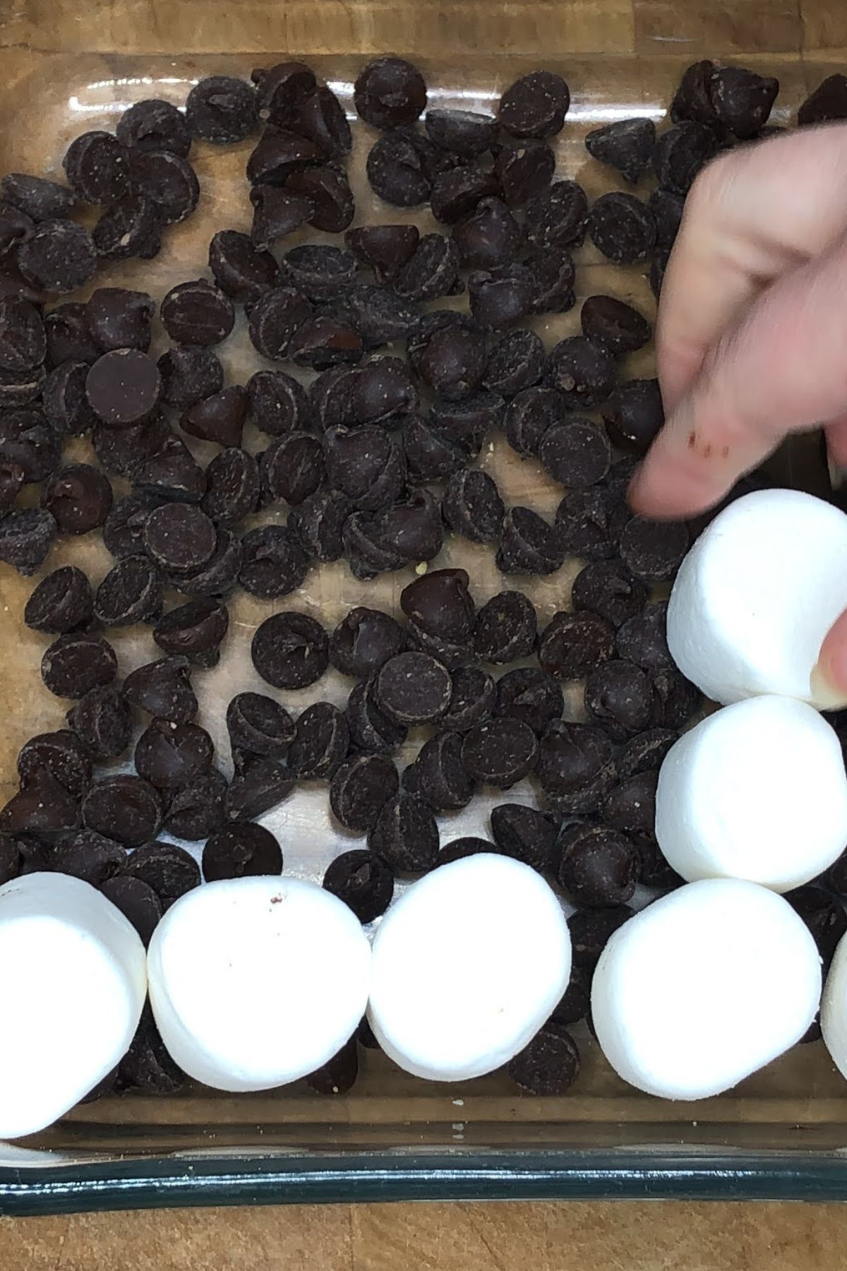 Placing marshmallows on top of chocolate chips in a pan.