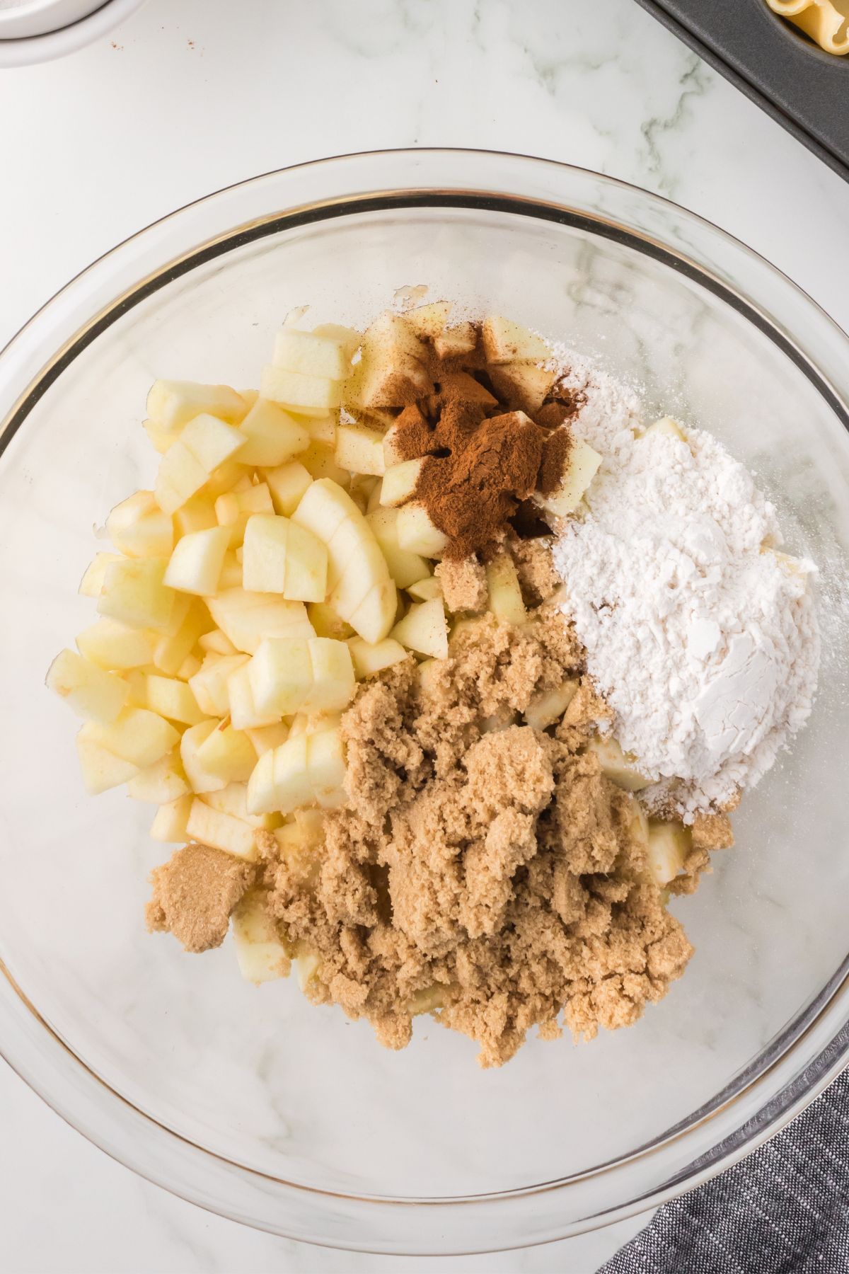 Diced apples and spices in a glass bowl.