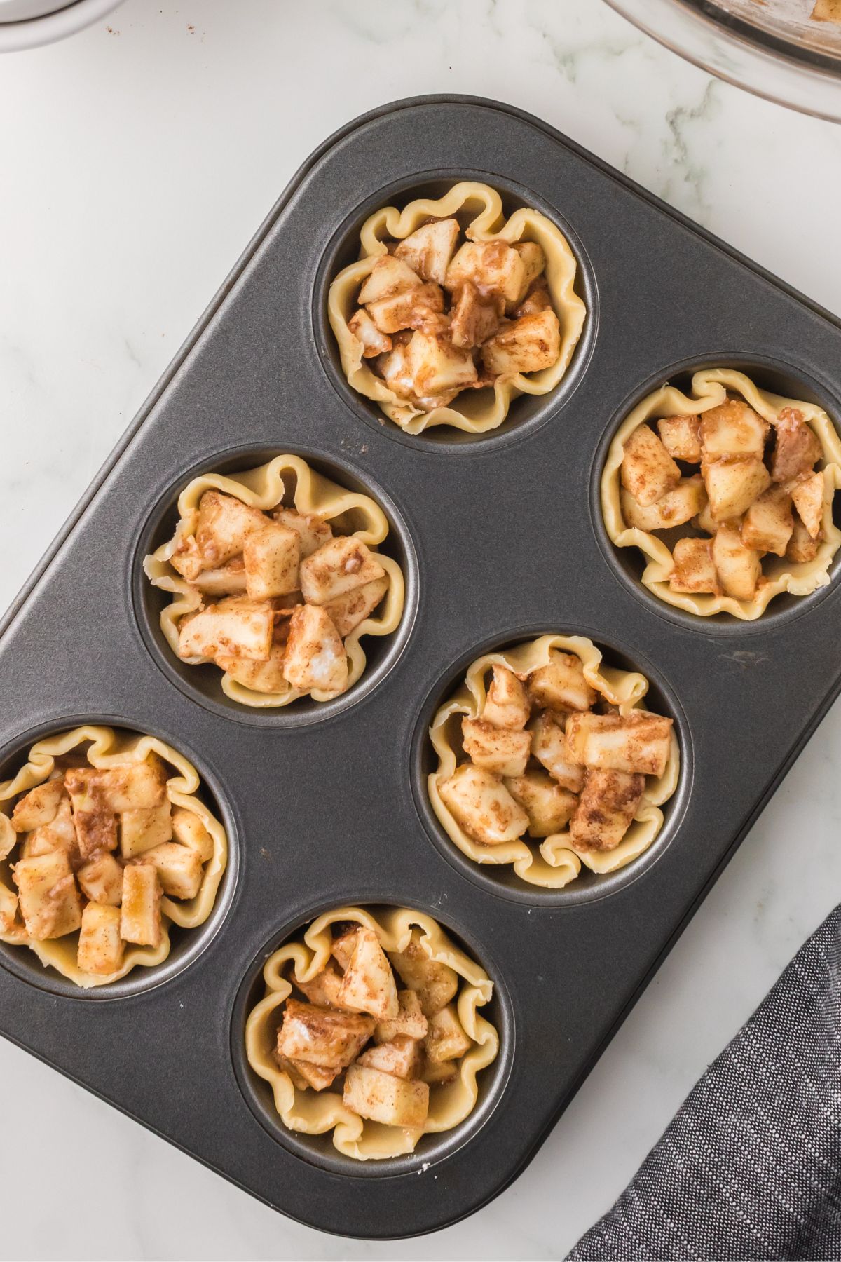 Mini apple pie tarts in a muffin tin without topping added.
