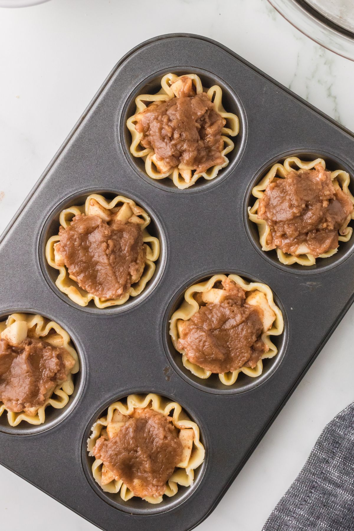 Mini apple pie tarts in a muffin tin.