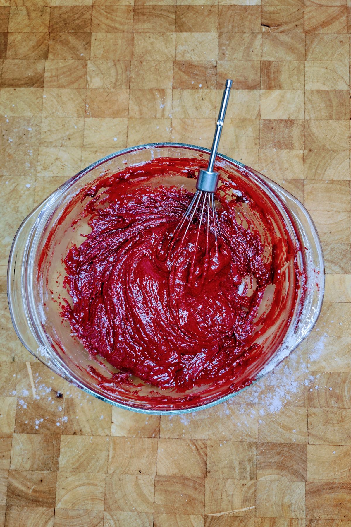 Red velvet brownie batter with whisk in mixing bowl.