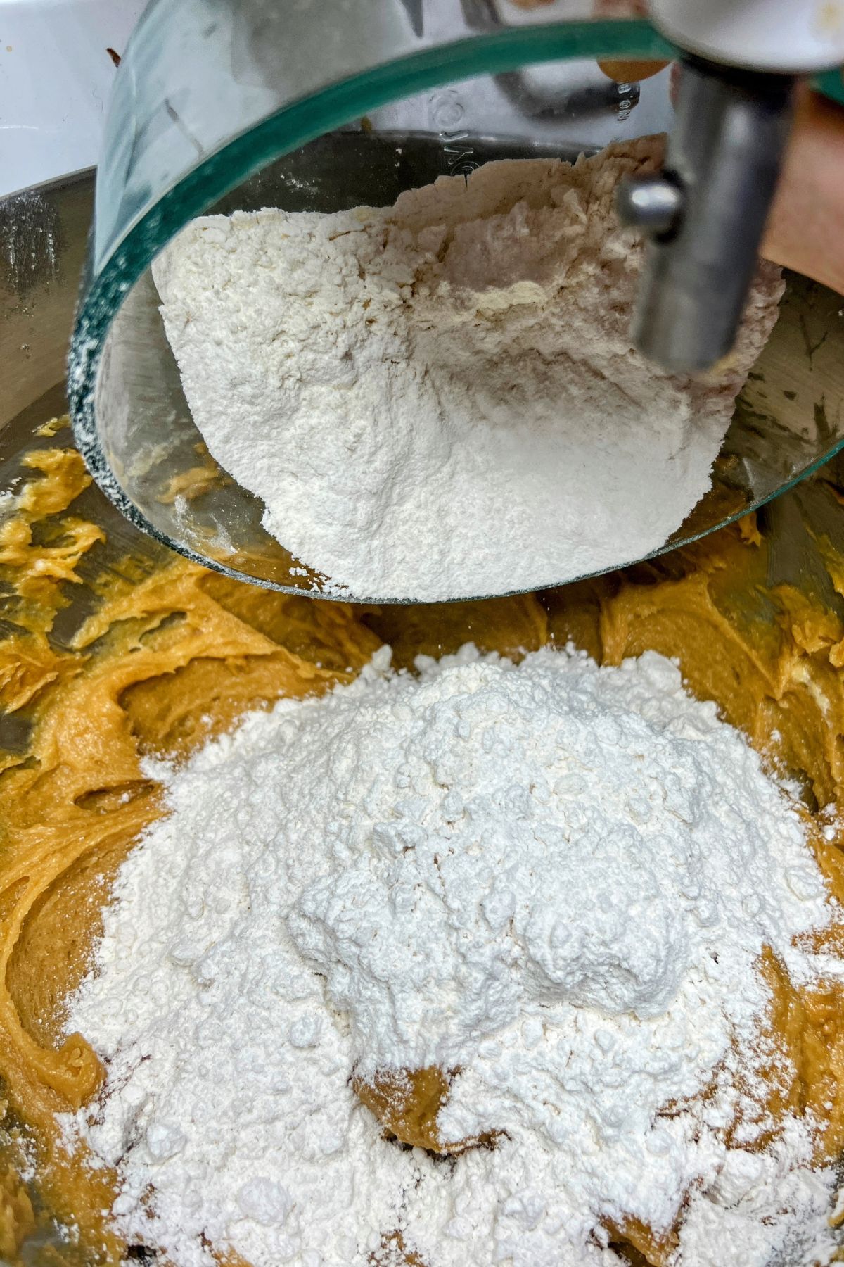 Adding flour to peanut butter cookie dough.