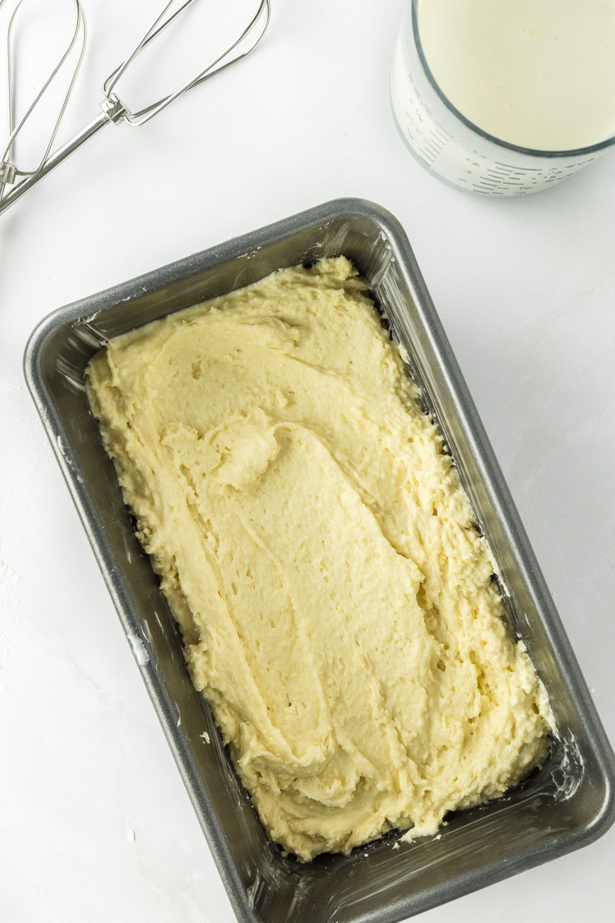 Whipped cream pound cake batter in a loaf pan.