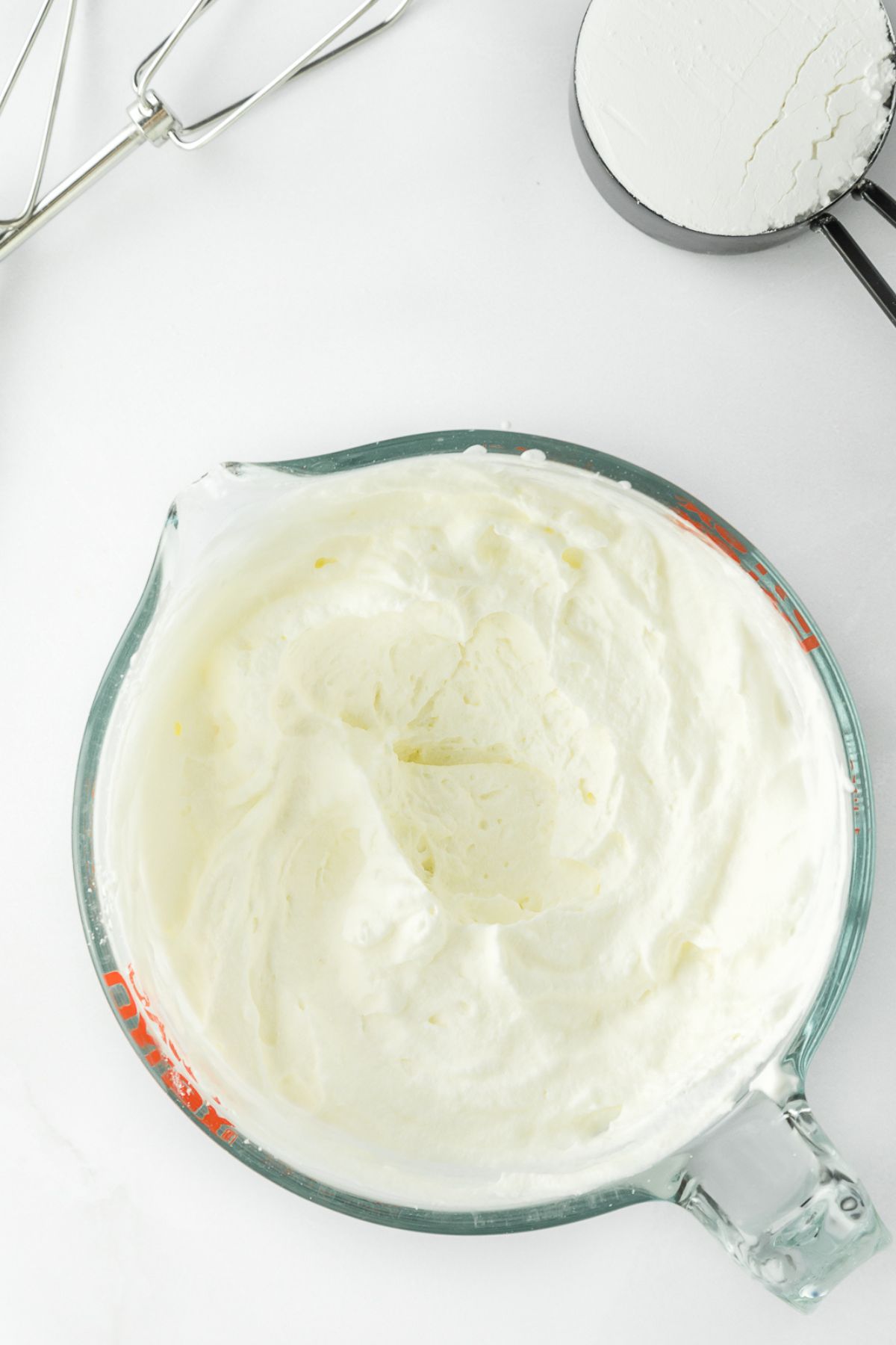 Whipped cream icing in a measuring cup.