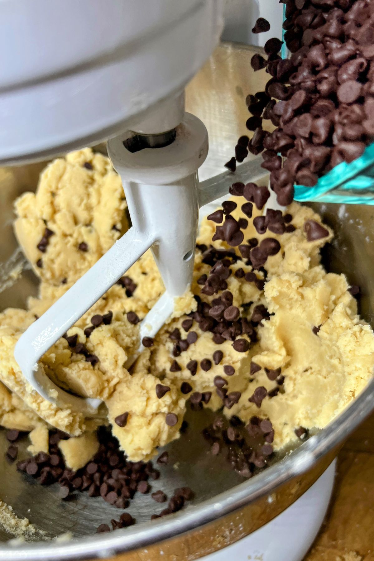 Pouring chocolate chips into cookie dough.