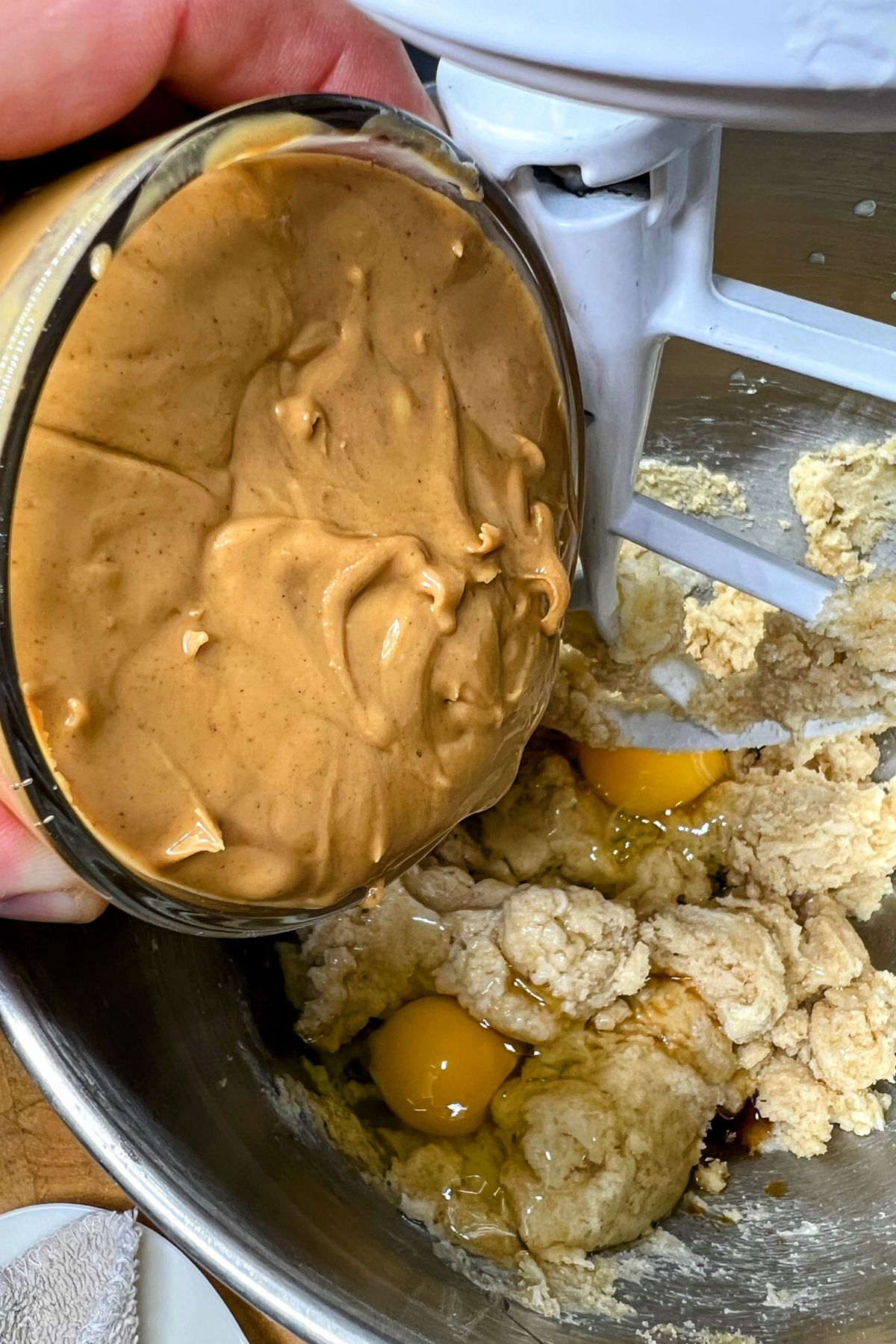 Eggs and peanut butter in a bowl with creamed butter and sugar.