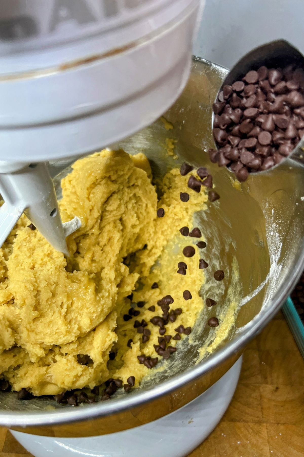 Adding chocolate chips into a bowl with cookie dough.