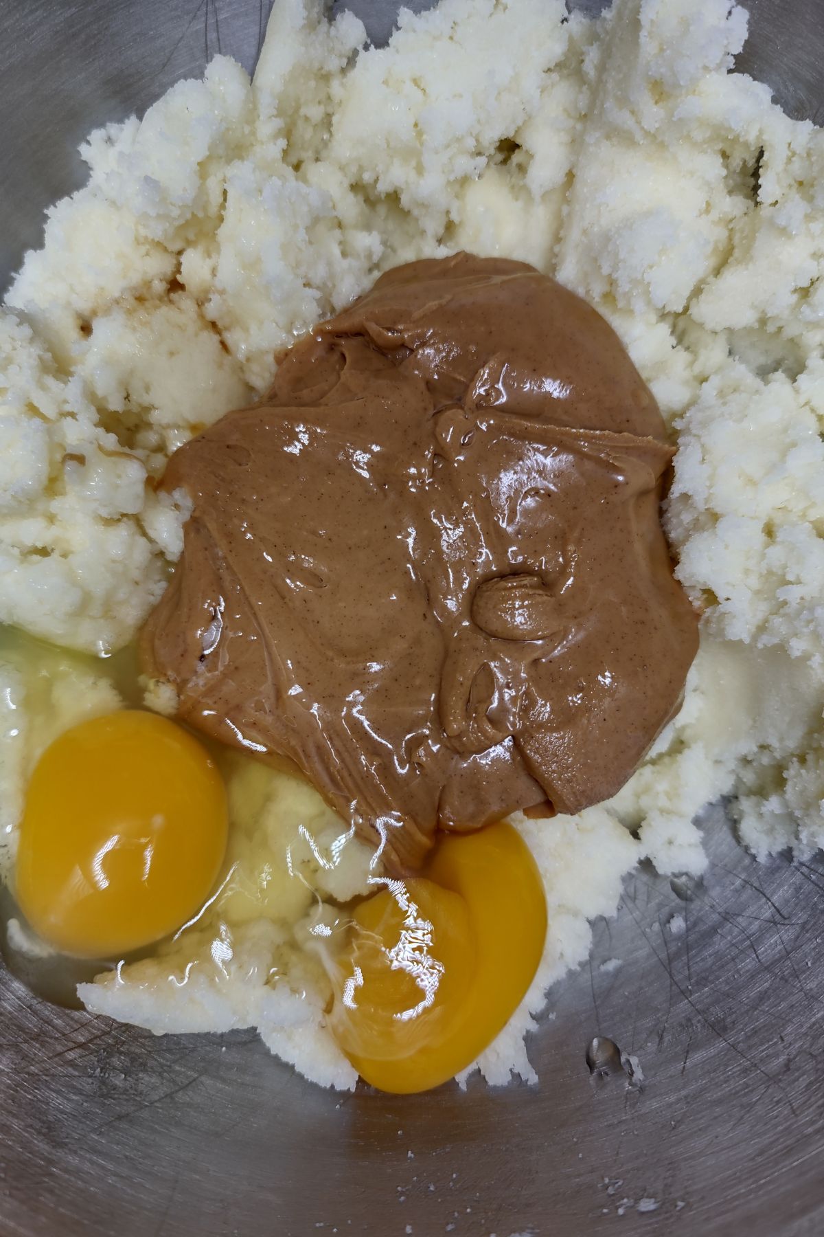 Creamed butter and sugar with peanut butter and eggs in a mixing bowl.