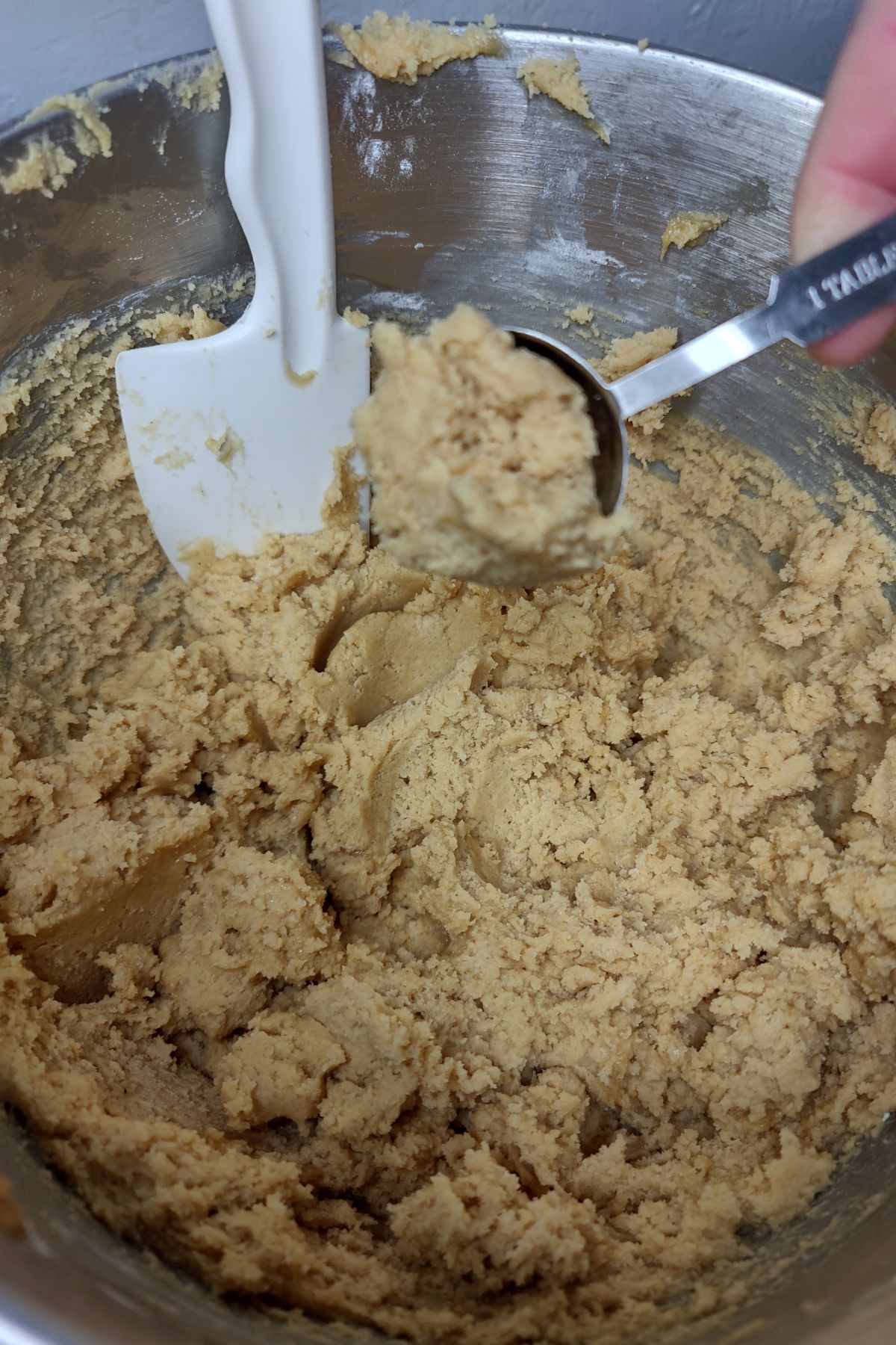 Scooping cookie dough with a tablespoon.