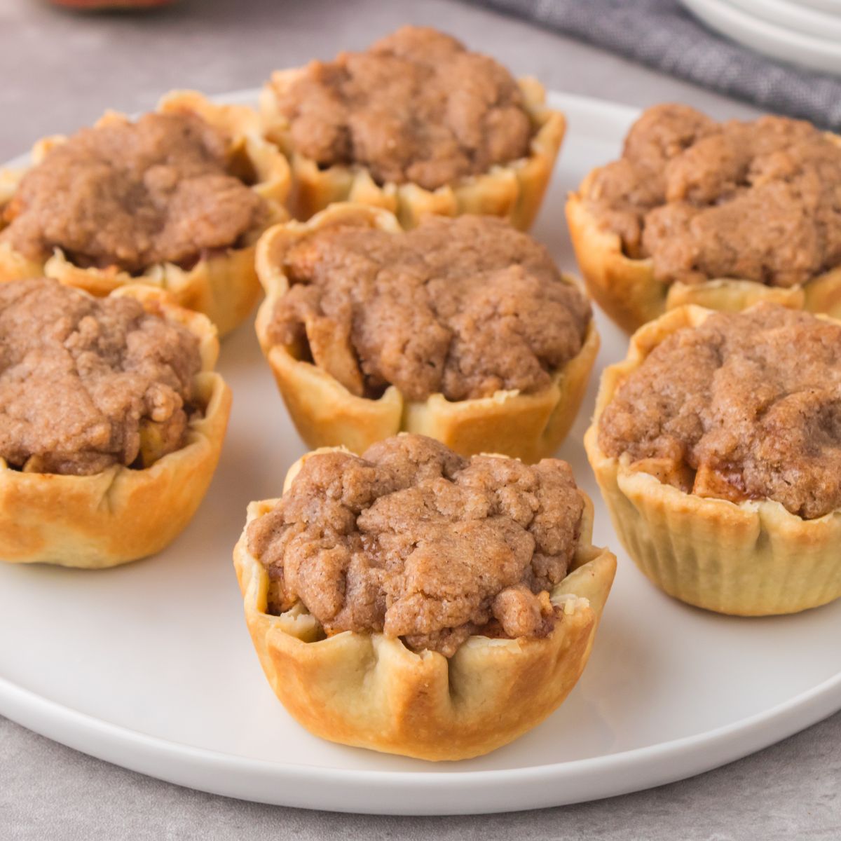 Mini apple pie tarts on a white plate.