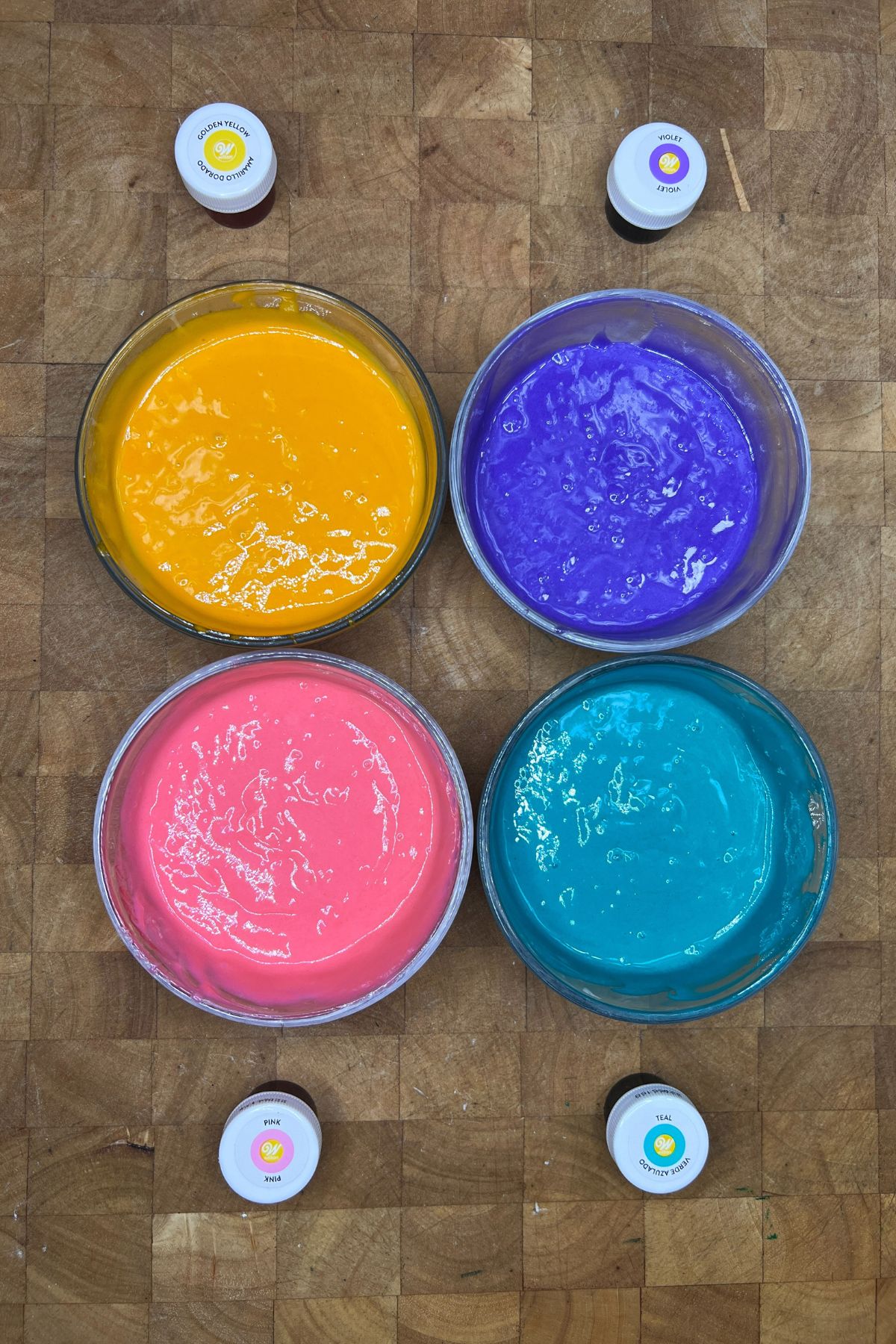 Mixing bowls with yellow, purple, pink and blue colored cake batter.