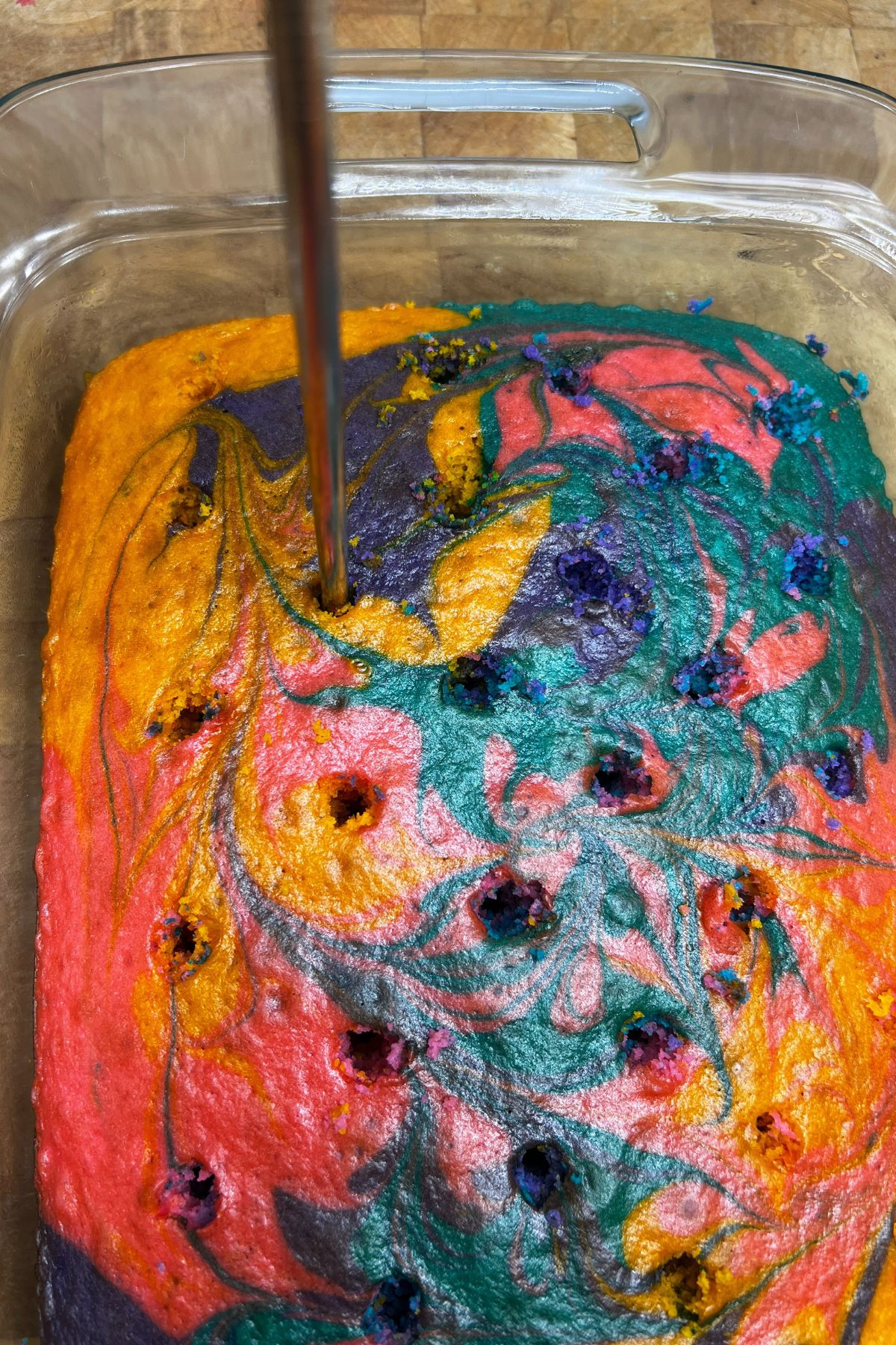 Poking holes in a colorful cake.