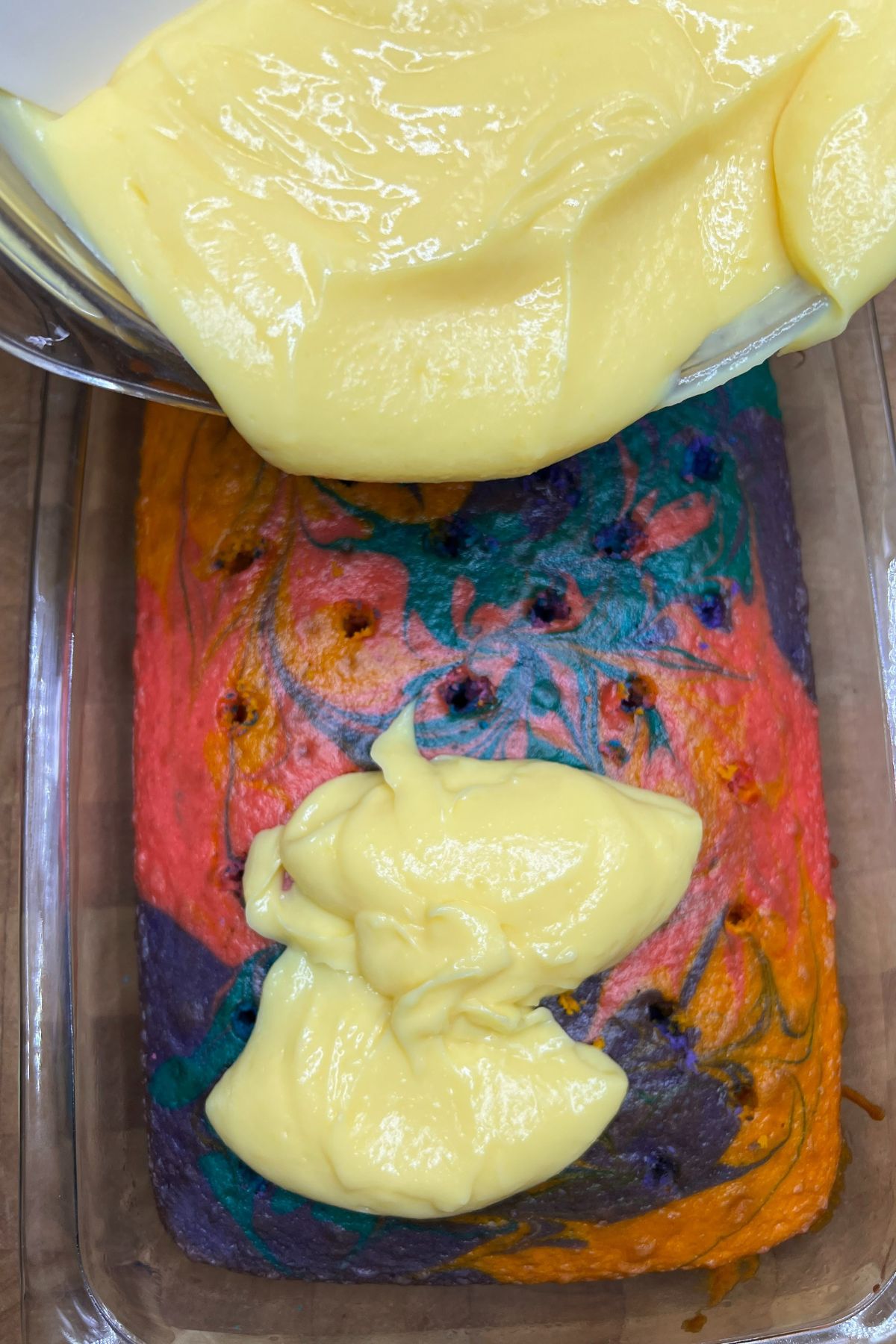 Pouring vanilla pudding onto easter colored cake.