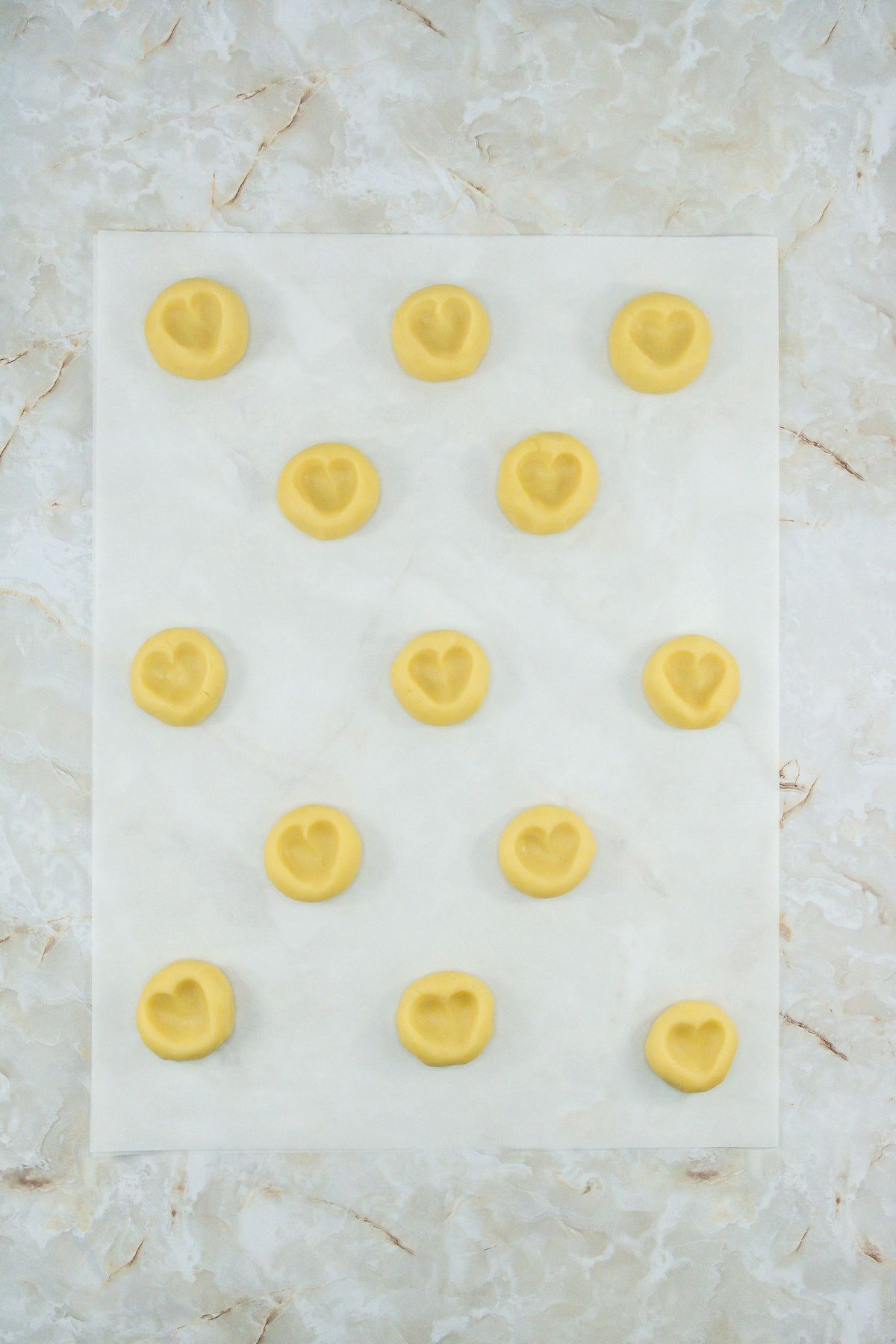 Cookies with hearts shaped in the dough on parchment paper.