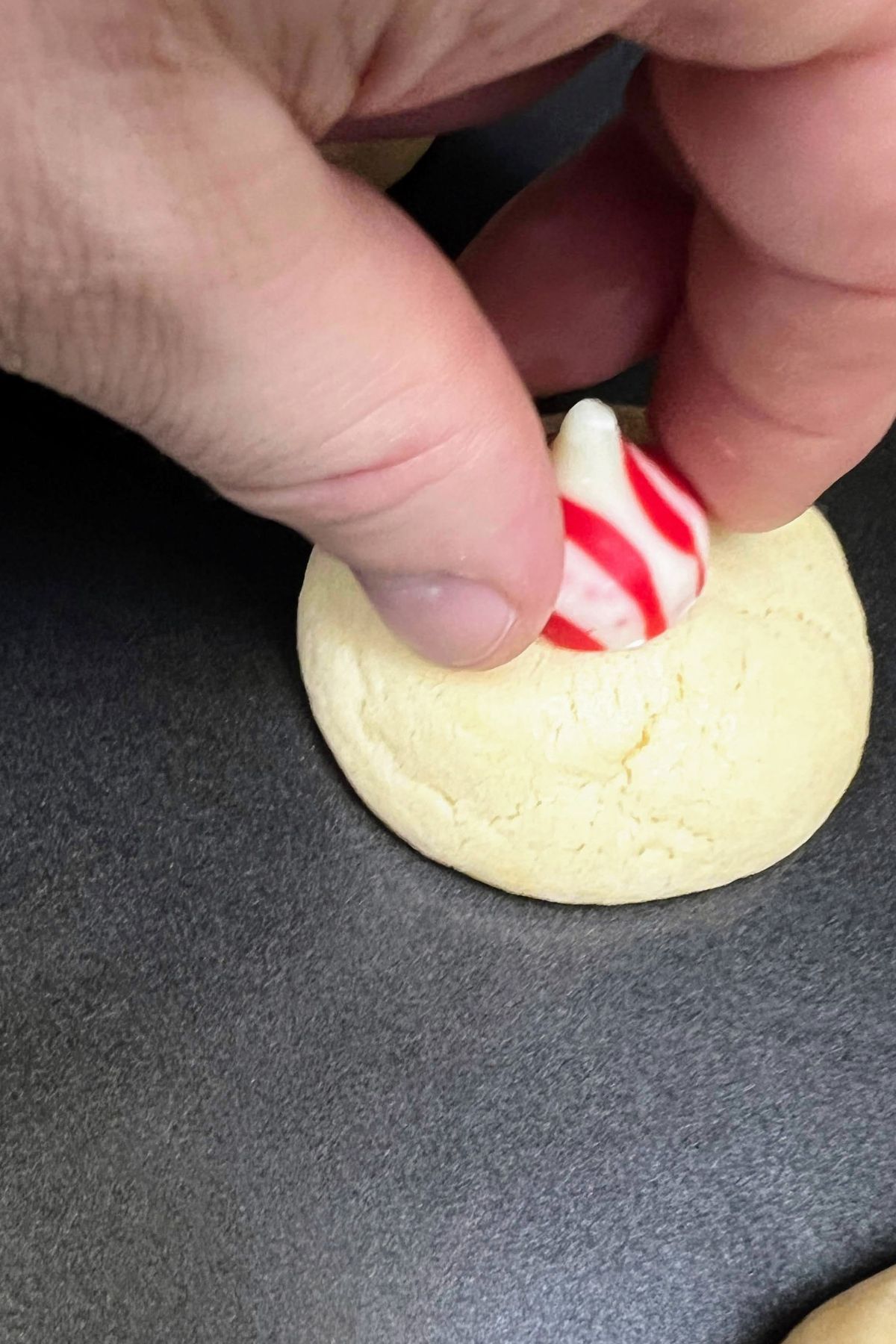 Adding a hershey kiss to a baked sugar cookie.