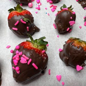 Nutella covered strawberries with sprinkles on parchment paper.