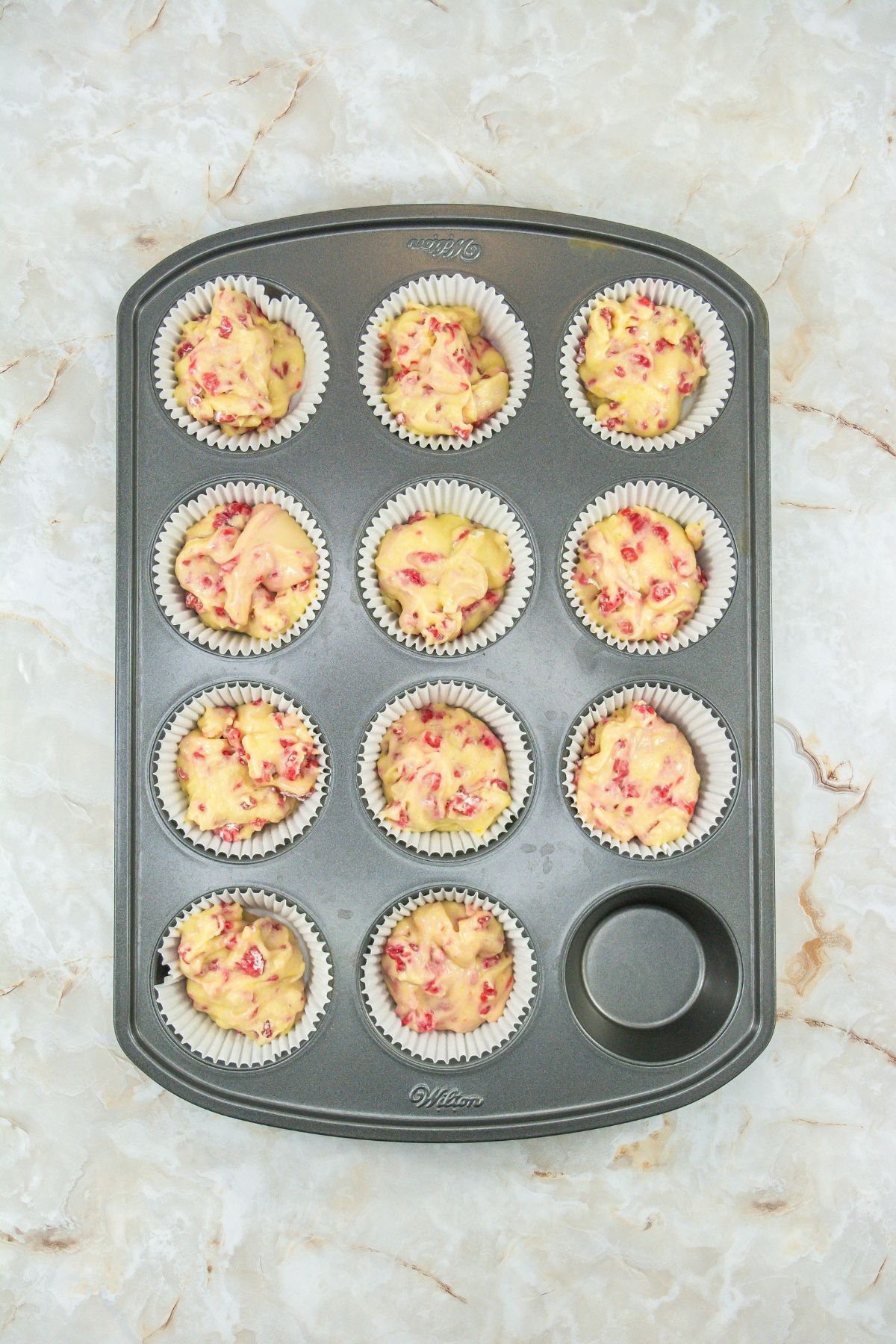Raspberry cupcake batter in a muffin tin.