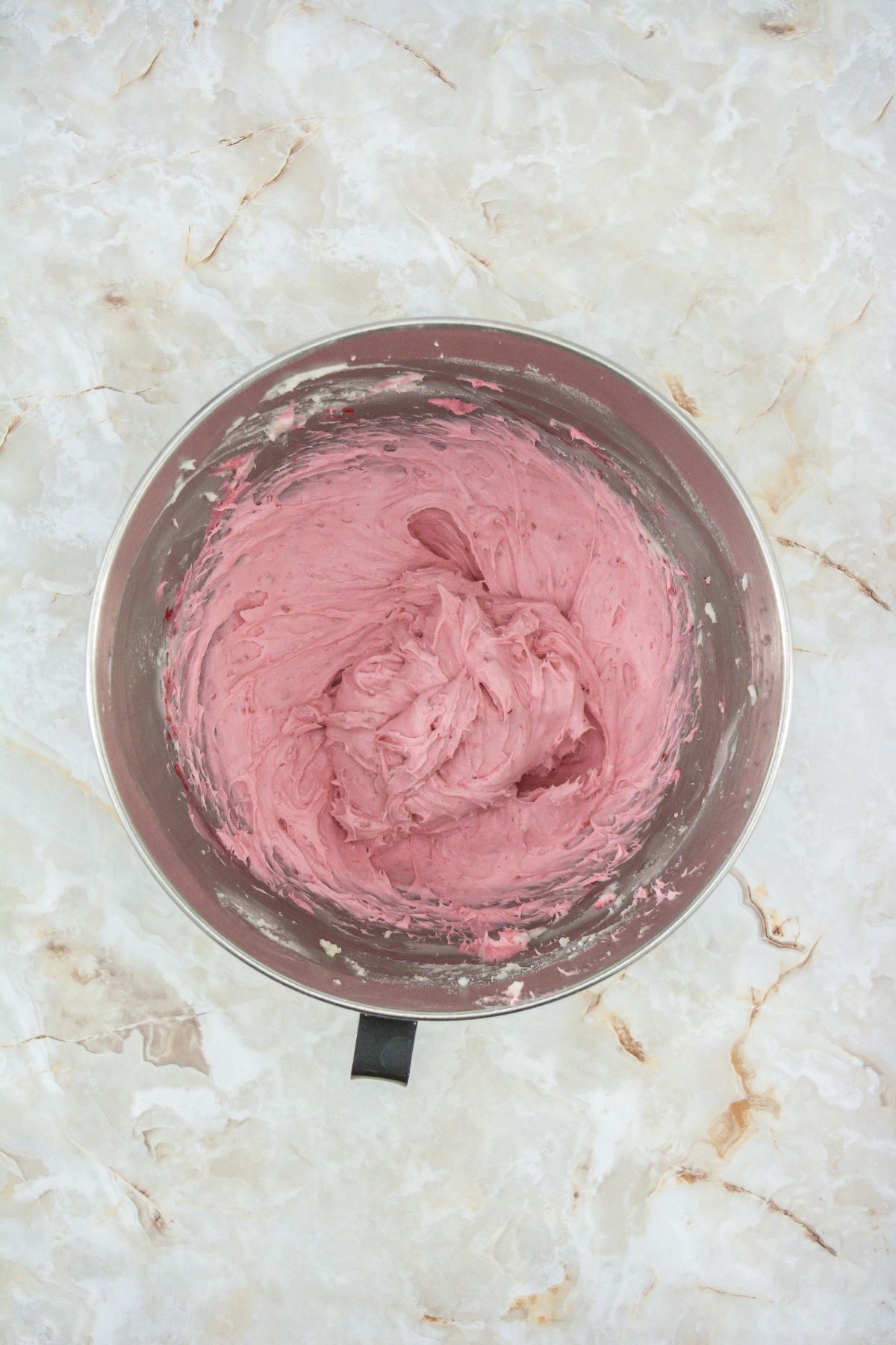 Raspberry frosting in a mixing bowl.