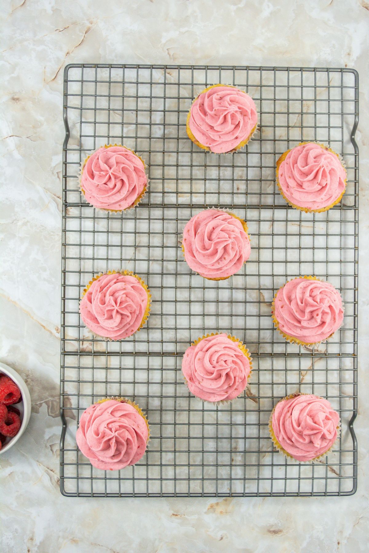 Raspberry cupcakes on a cooling rack.