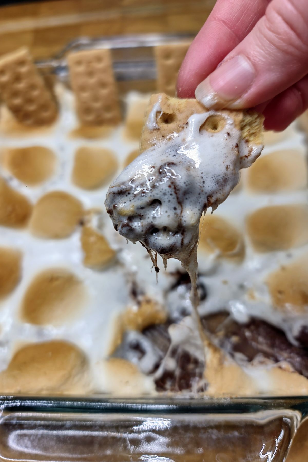 Dipping graham cracker into smores dip.