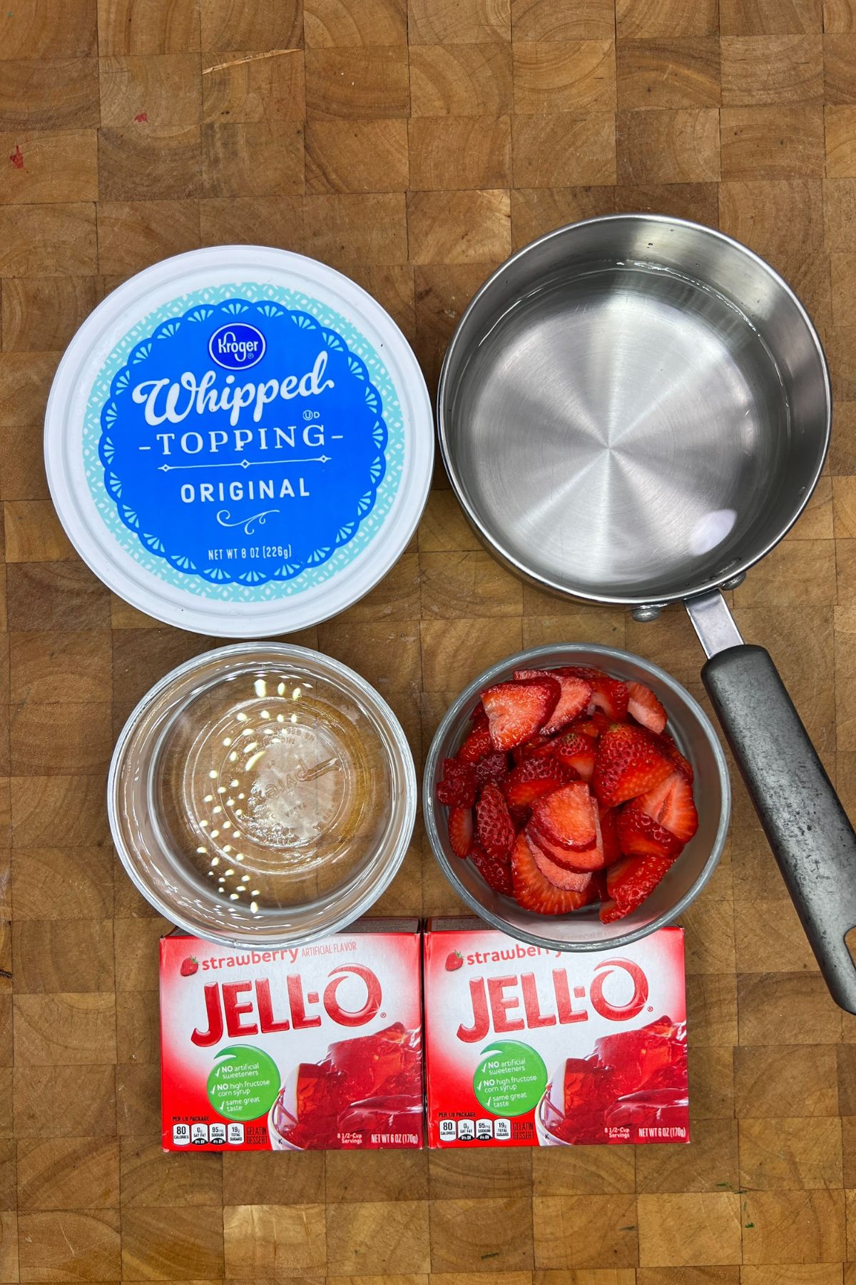 Ingredients for strawberry jello salad on a wooden table.