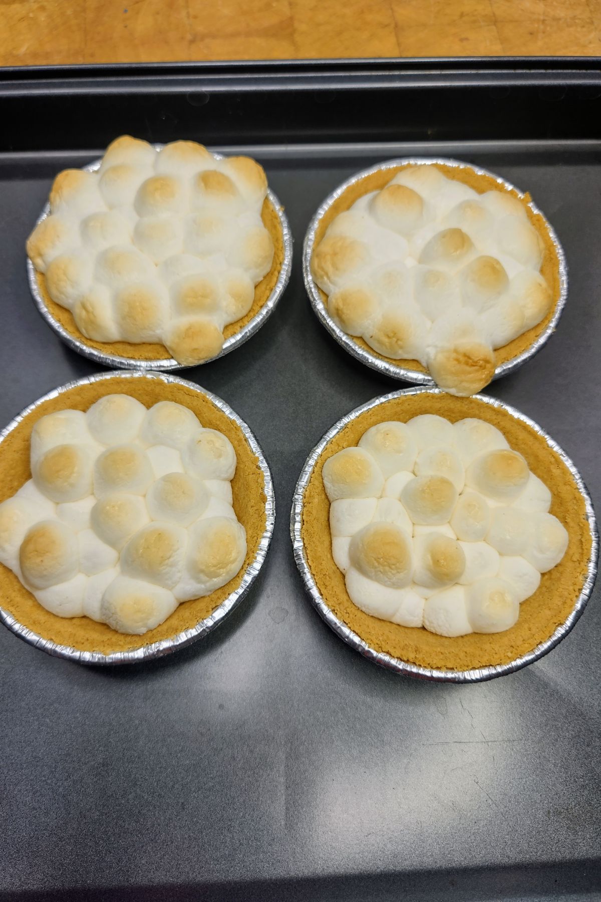 Four mini smores pies on a cookie sheet.