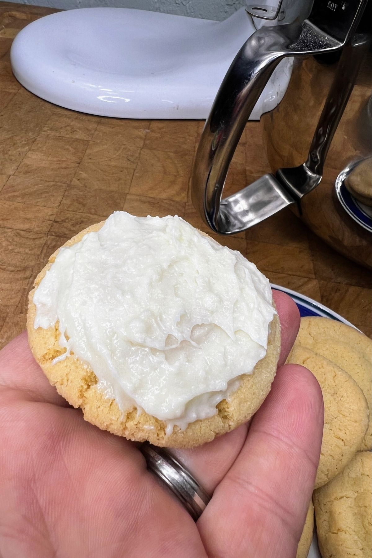 Spreading cream cheese frosting on a sugar cookie.
