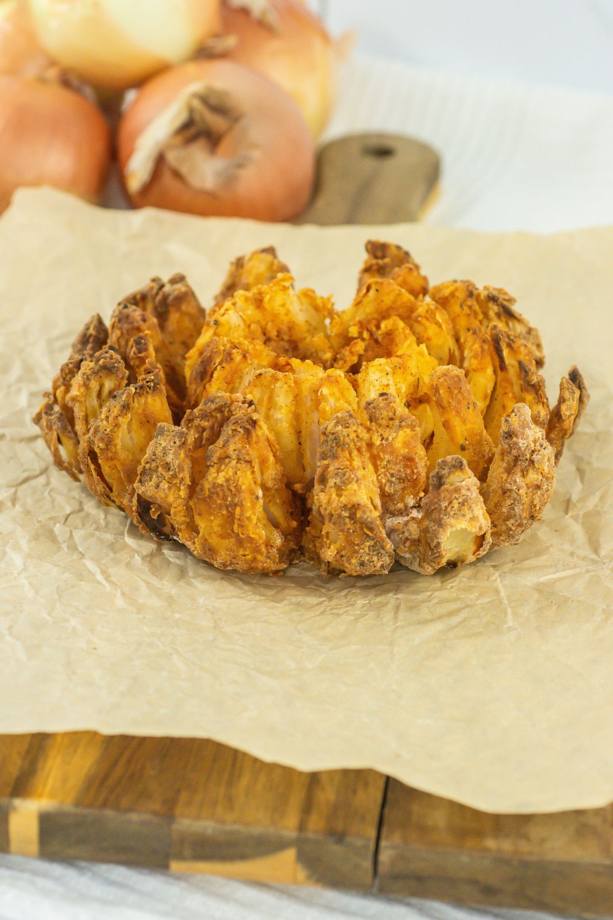 Air fryer blooming onion on a wood board.
