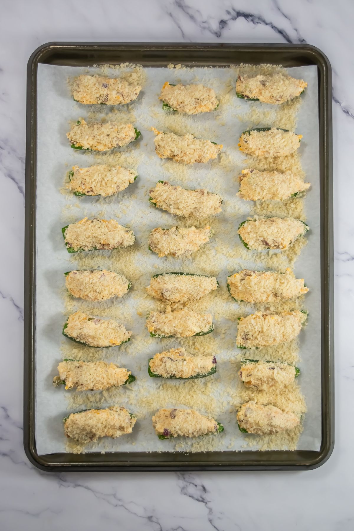 Cheese sprinkled on top of peppers on a baking sheet.