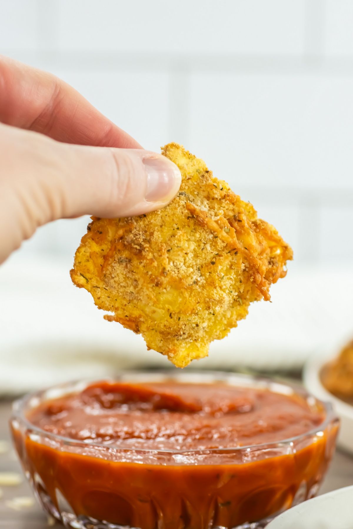 Air fryer ravioli being dipped into sauce.