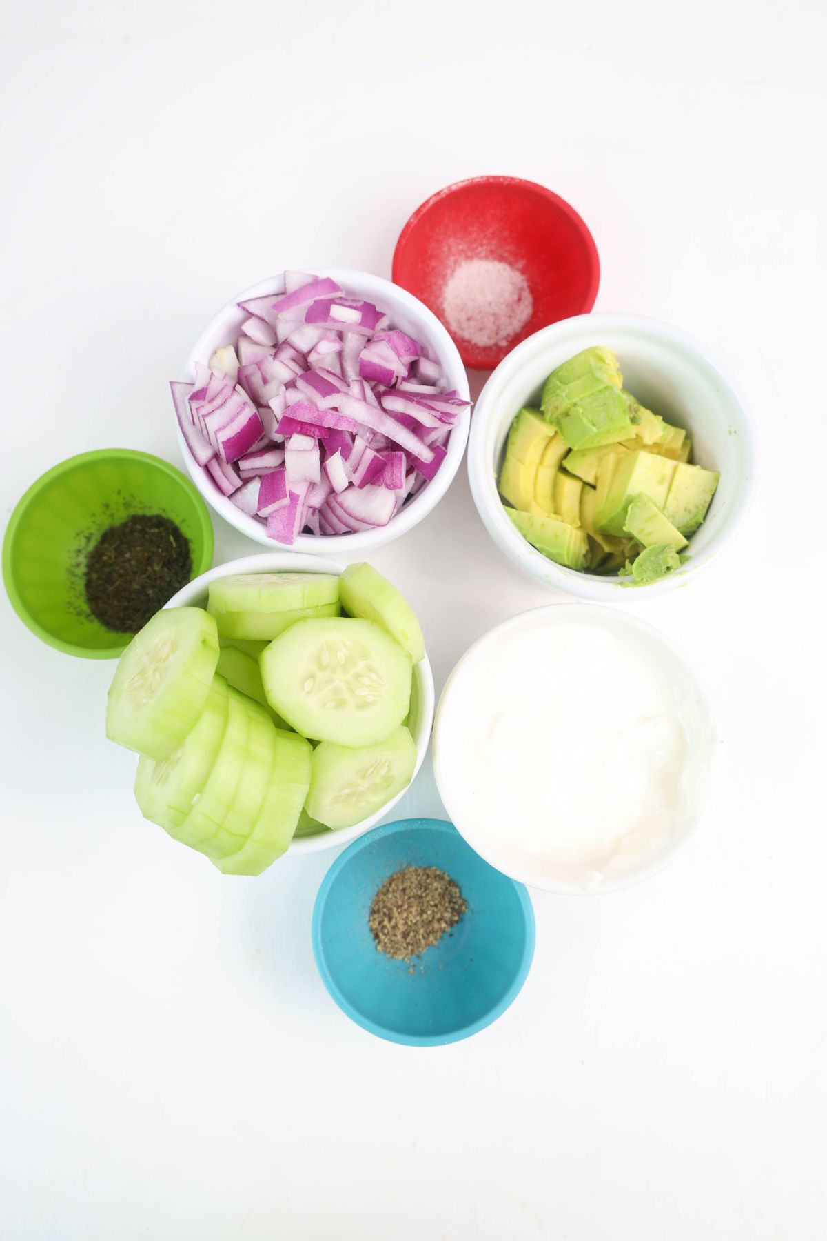 Avocado cucumber salad ingredients on a white counter.