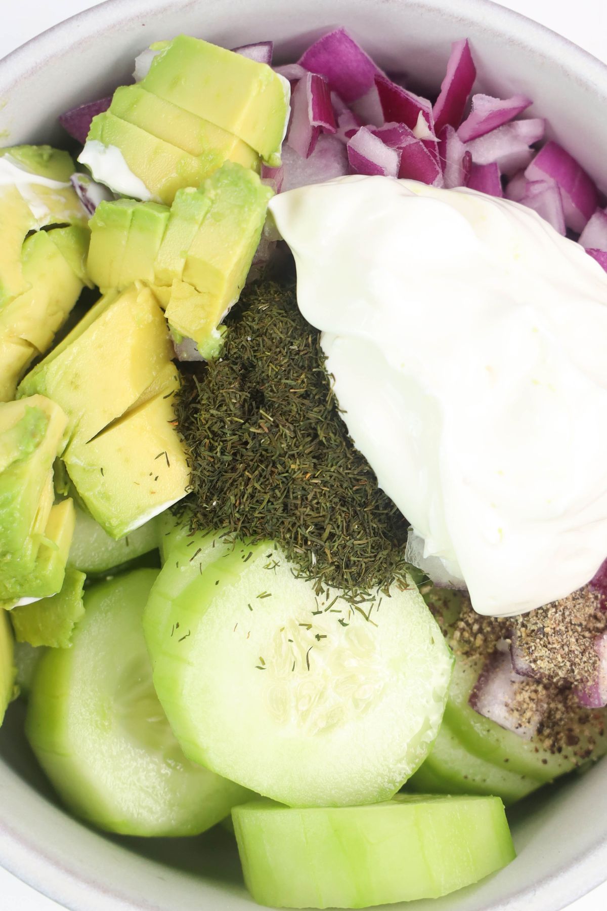 Avocado cucumber salad ingredients in a bowl.