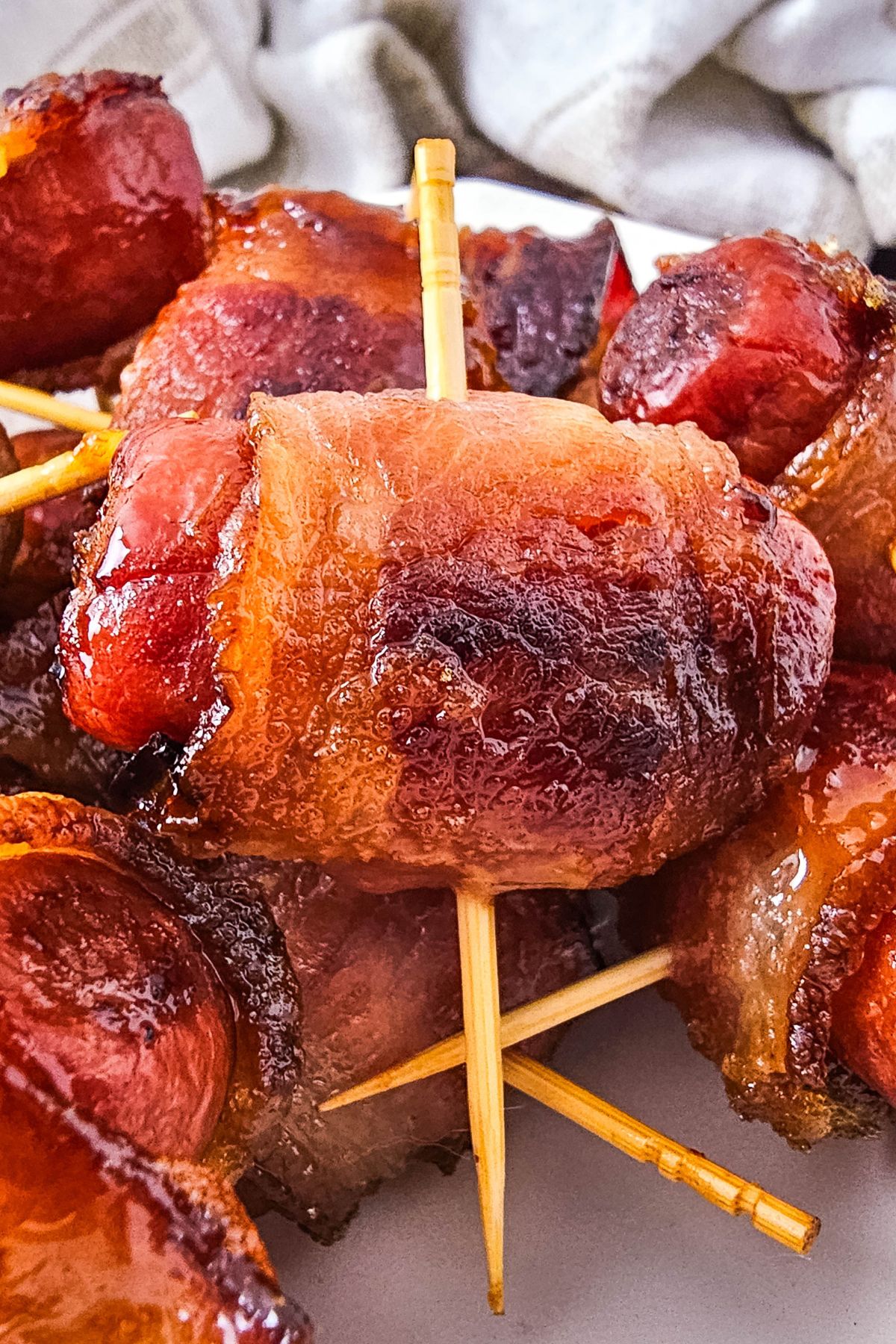 Bacon wrapped smokies in a pile on a plate.